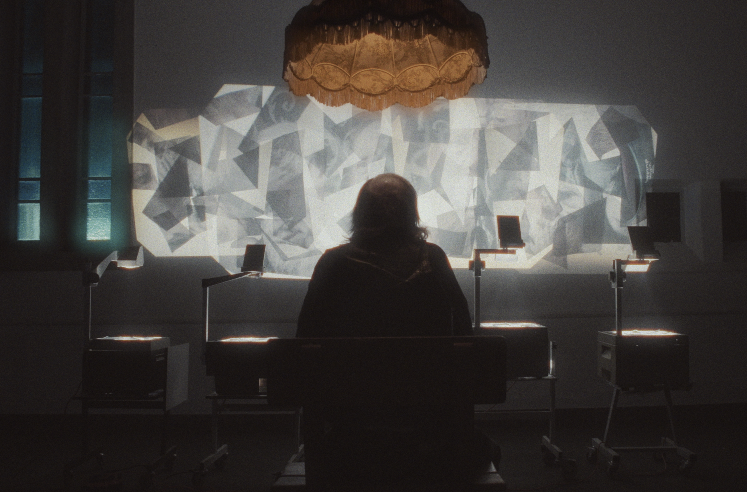 En person sidder foran en projektor, der viser et abstrakt, geometrisk sort-hvidt billede på væggen i et mørkt studie | Dokumentarfilm | Retrograd | Esben Persson & Anders Mielcke | Filmproduktion Aarhus | GESTALT
