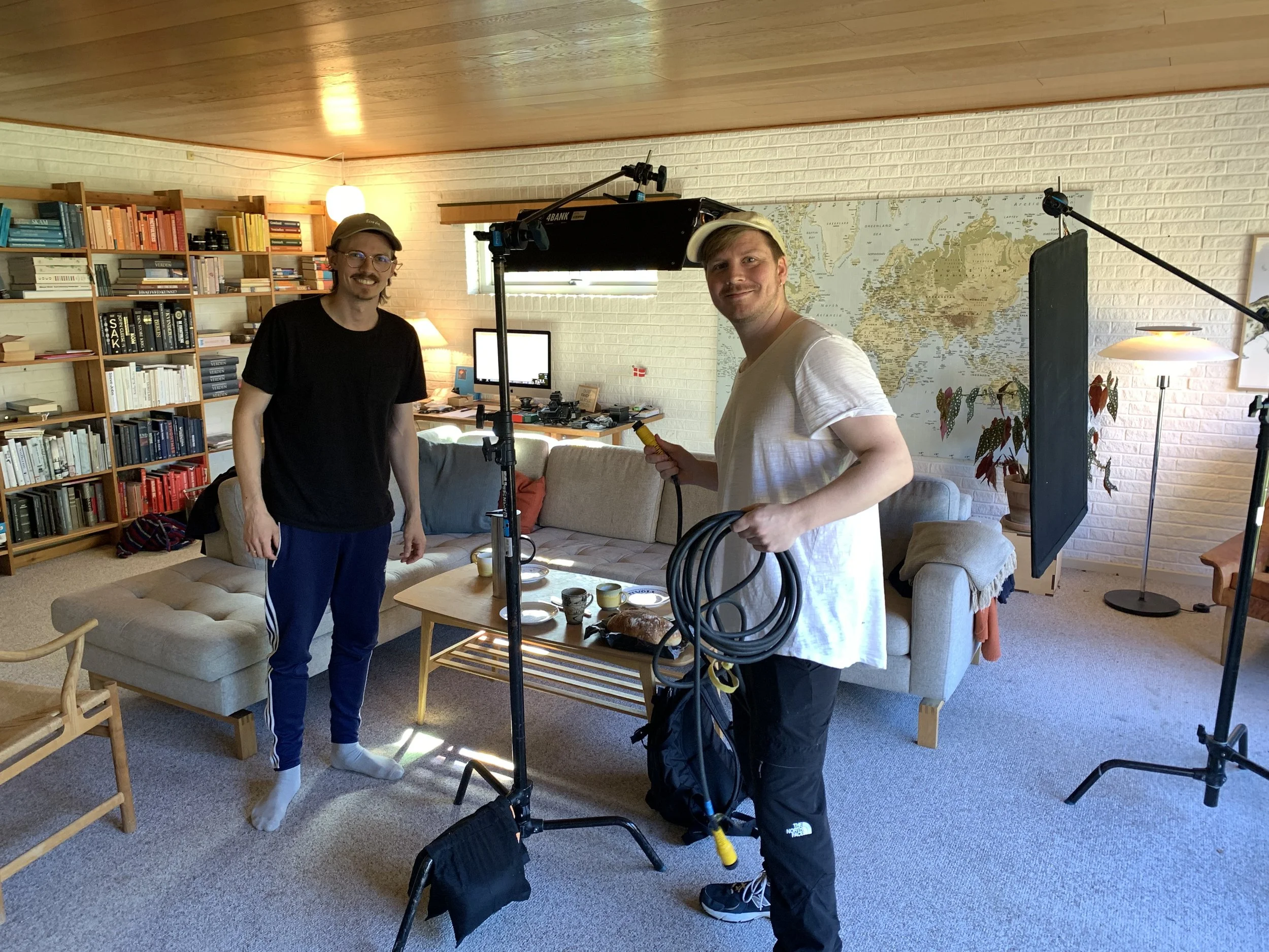 To mænd arbejder på en filmoptagelse i en stue med bogreoler, sofa og et stort kort på væggen | Dokumentarfilm | Retrograd | Esben Persson & Anders Mielcke | Filmproduktion Aarhus | GESTALT