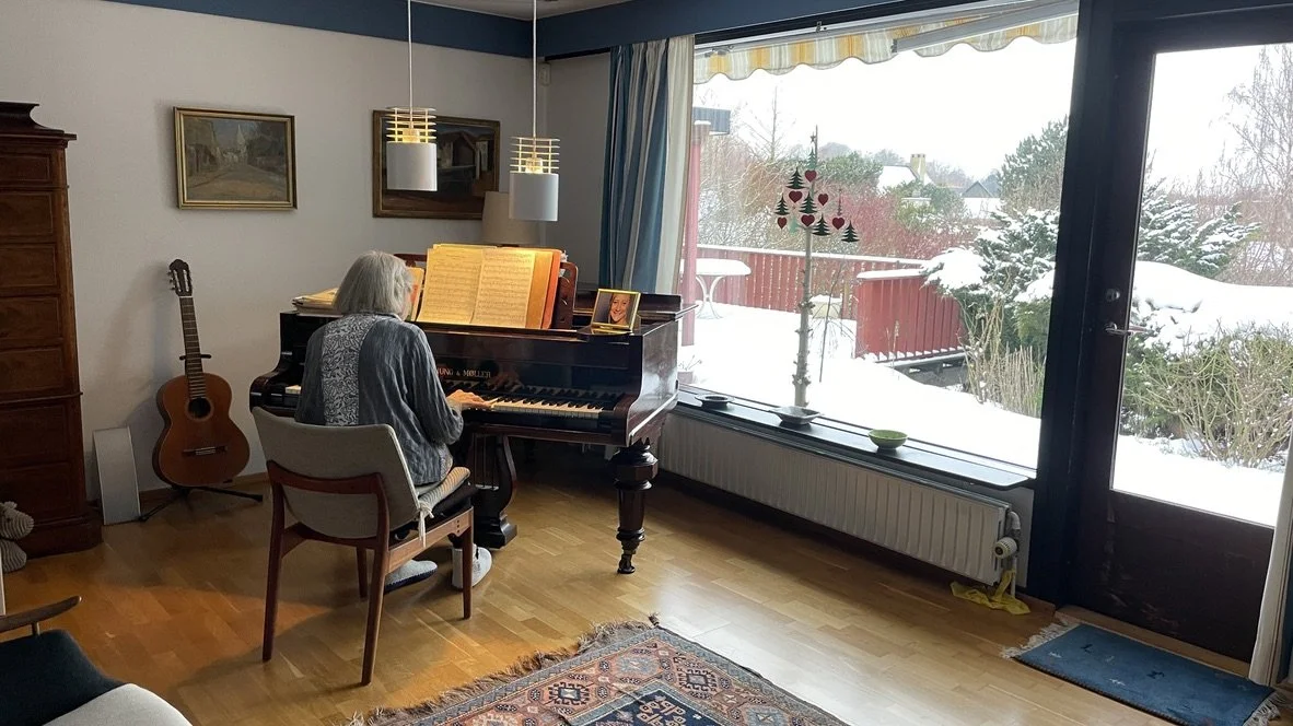 Person spiller klaver i et hyggeligt hjem, med snedække udenfor gennem store vinduer | Dokumentarfilm | Retrograd | Esben Persson & Anders Mielcke  | Filmproduktion Aarhus | GESTALT