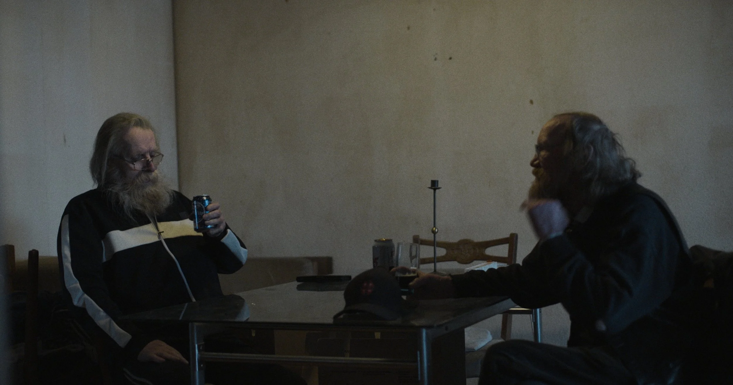 To mænd sidder ved et bord i et mørkt rum, den ene holder en dåse | Dokumentarfilm | Retrograd | Esben Persson & Anders Mielcke | Filmproduktion Aarhus | GESTALT