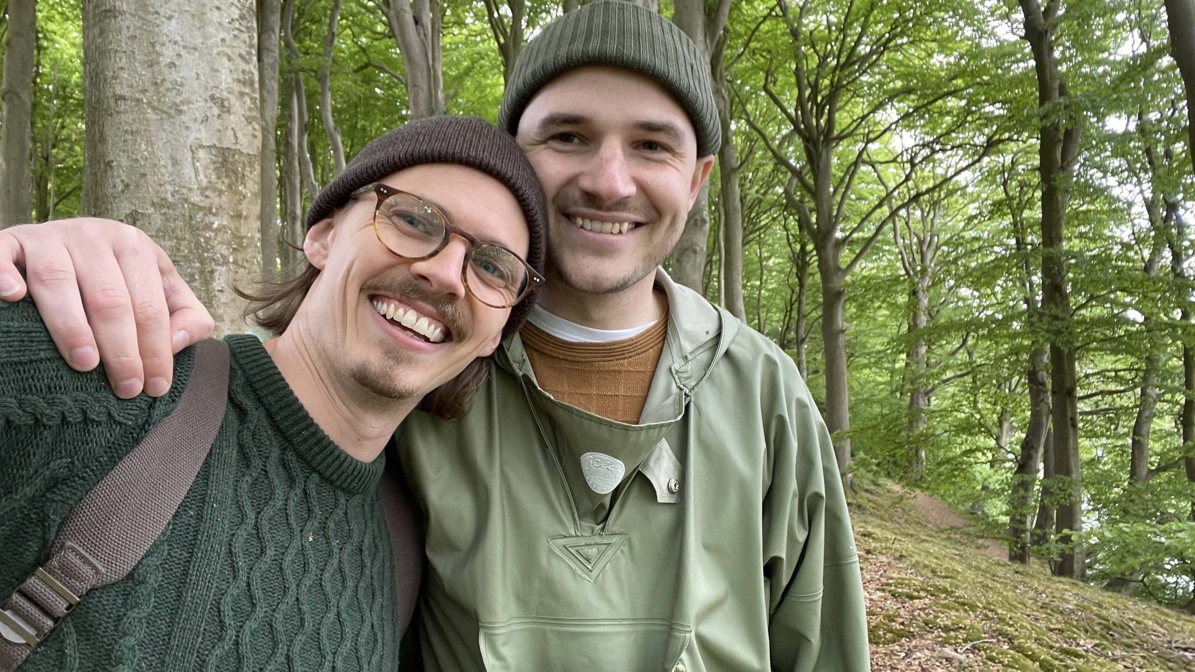 To mænd tager selfie i skov med grønne blade og træer i baggrunden | Bagom billeder | Filmproduktion | GESTALT