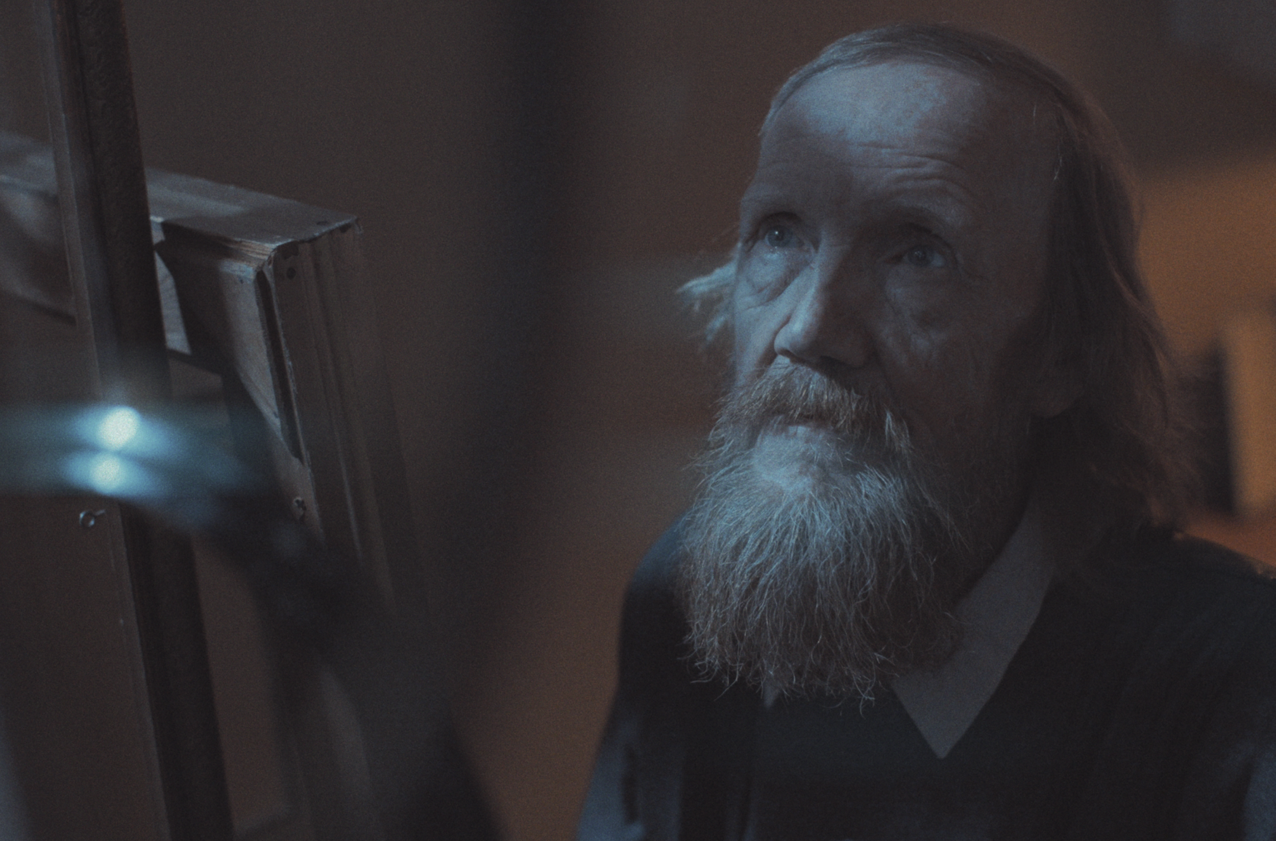 En ældre mand med langt, gråt hår og skæg ser opmærksomt på tomme billedrammer | Dokumentarfilm | Retrograd | Esben Persson & Anders Mielcke | Filmproduktion Aarhus | GESTALT