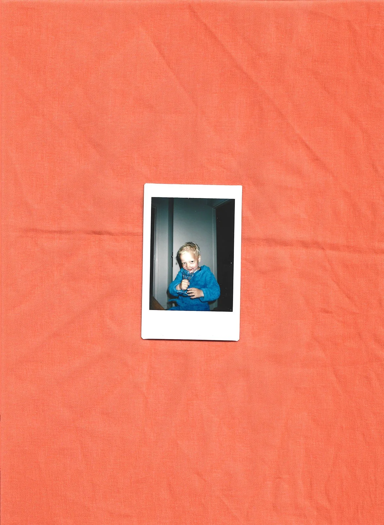 Billedet viser en lille dreng med blond hår, iført en blå pyjamas, der står inde i et rum og holder en is i hånden. Baggrunden er en væg med døre | Stemningsbillede | Filmproduktion i Aarhus | GESTALT