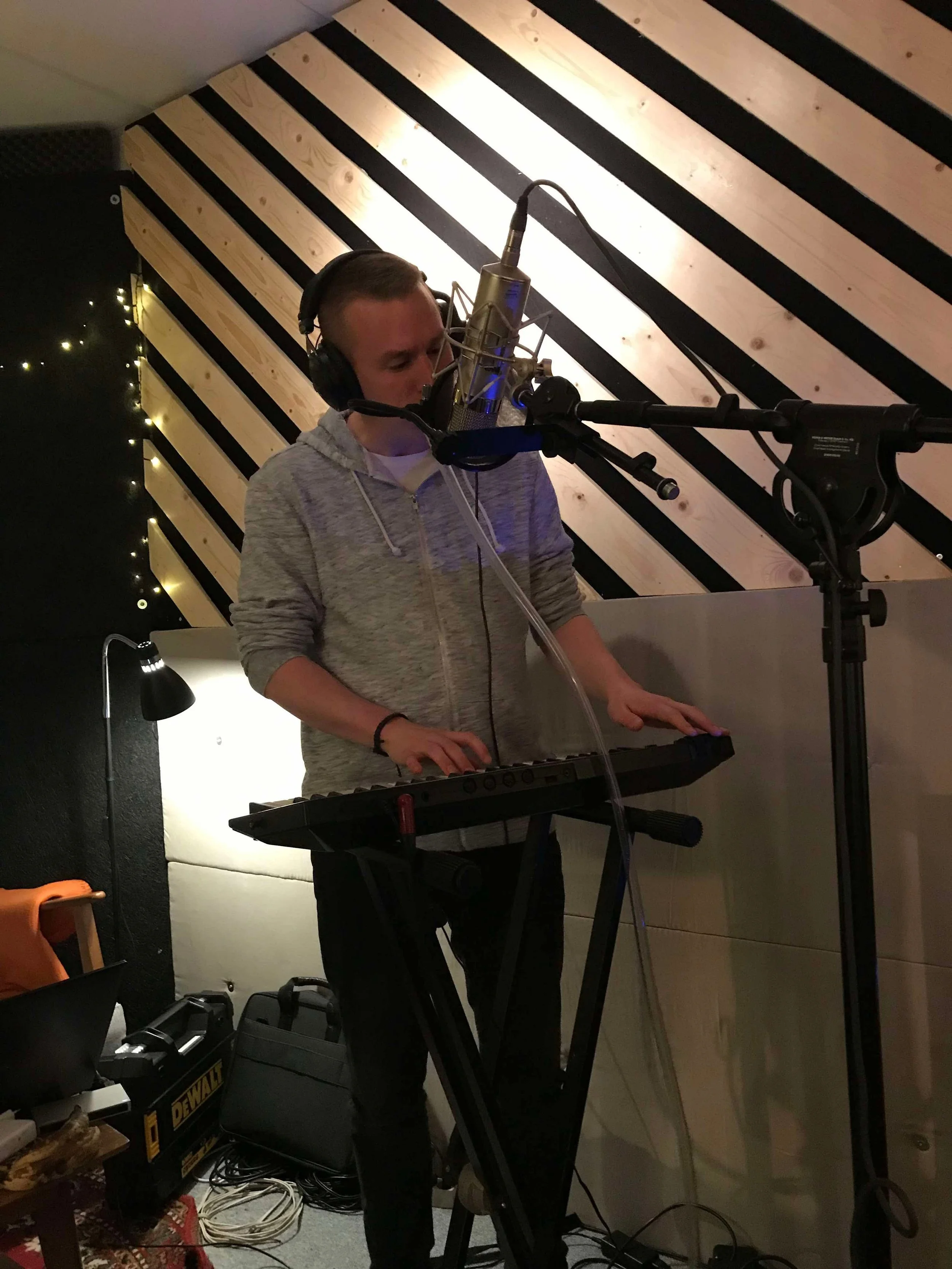 Person, der synger i et studie og spiller synth, med mikrofon foran | Studieproduktion | Musikkomposition | Filmproduktion Aarhus | GESTALT