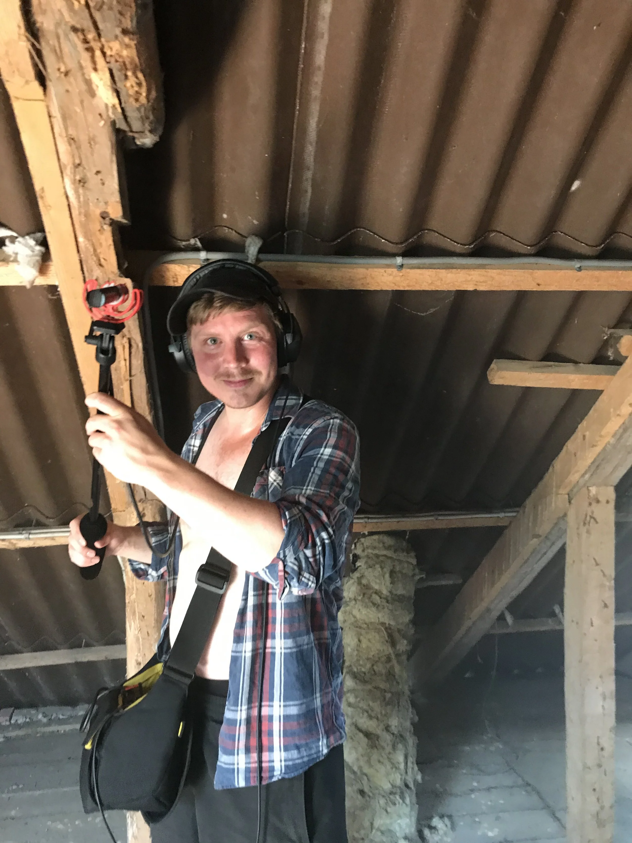 En mand med høretelefoner og med boomstang i hånden står i et loftsrum | Kortfilm | Wild Wild Vesløs | Esben Persson | Filmproduktion Aarhus | GESTALT