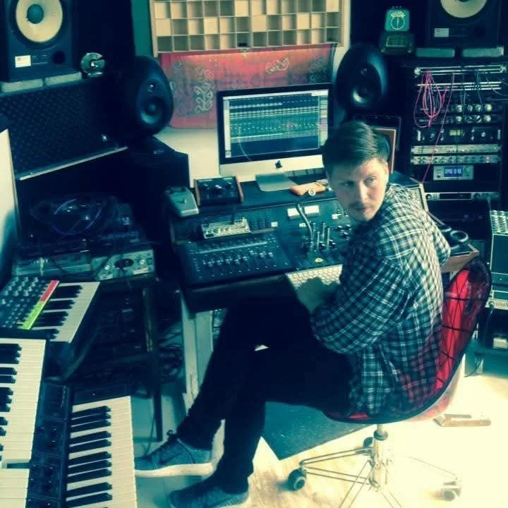 Person i et lydstudie med musikudstyr, herunder keyboard, computer med lydsoftware, mikrofoner og lydkontroludstyr | Studieproduktion | Musikkomposition | Filmproduktion Aarhus | GESTALT