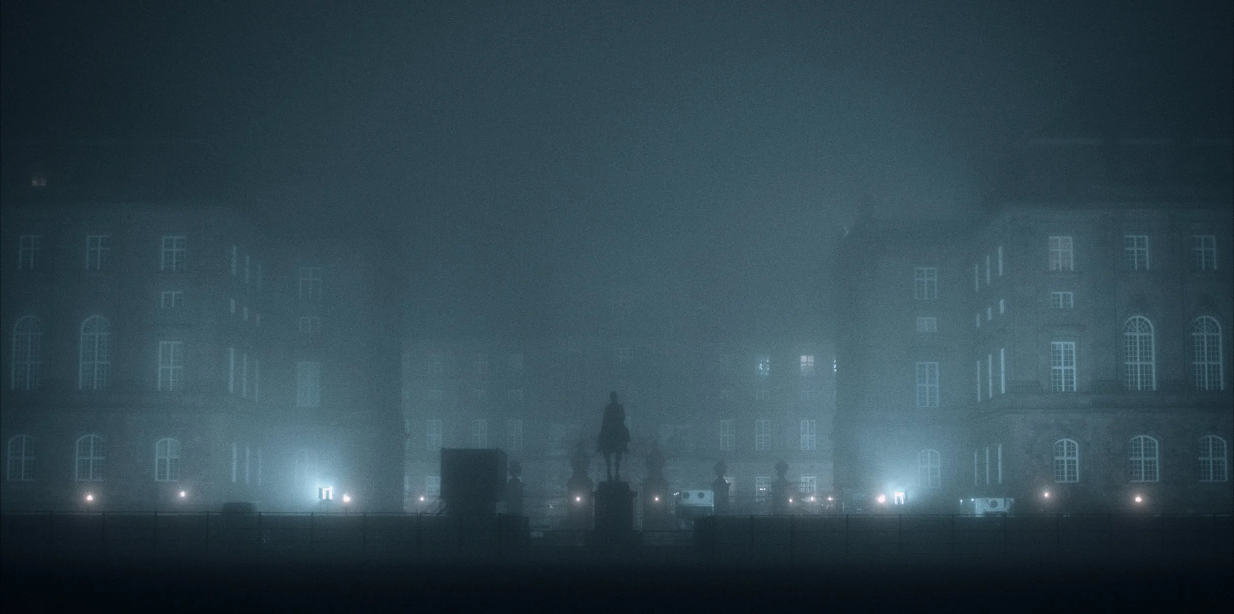 Et mørkt, tåget København med en statue af en hest og en mand til hest i midten. Christiansborg ses bagved | Dokumentarfilm | Retrograd | Esben Persson & Anders Mielcke | Filmproduktion Aarhus | GESTALT 