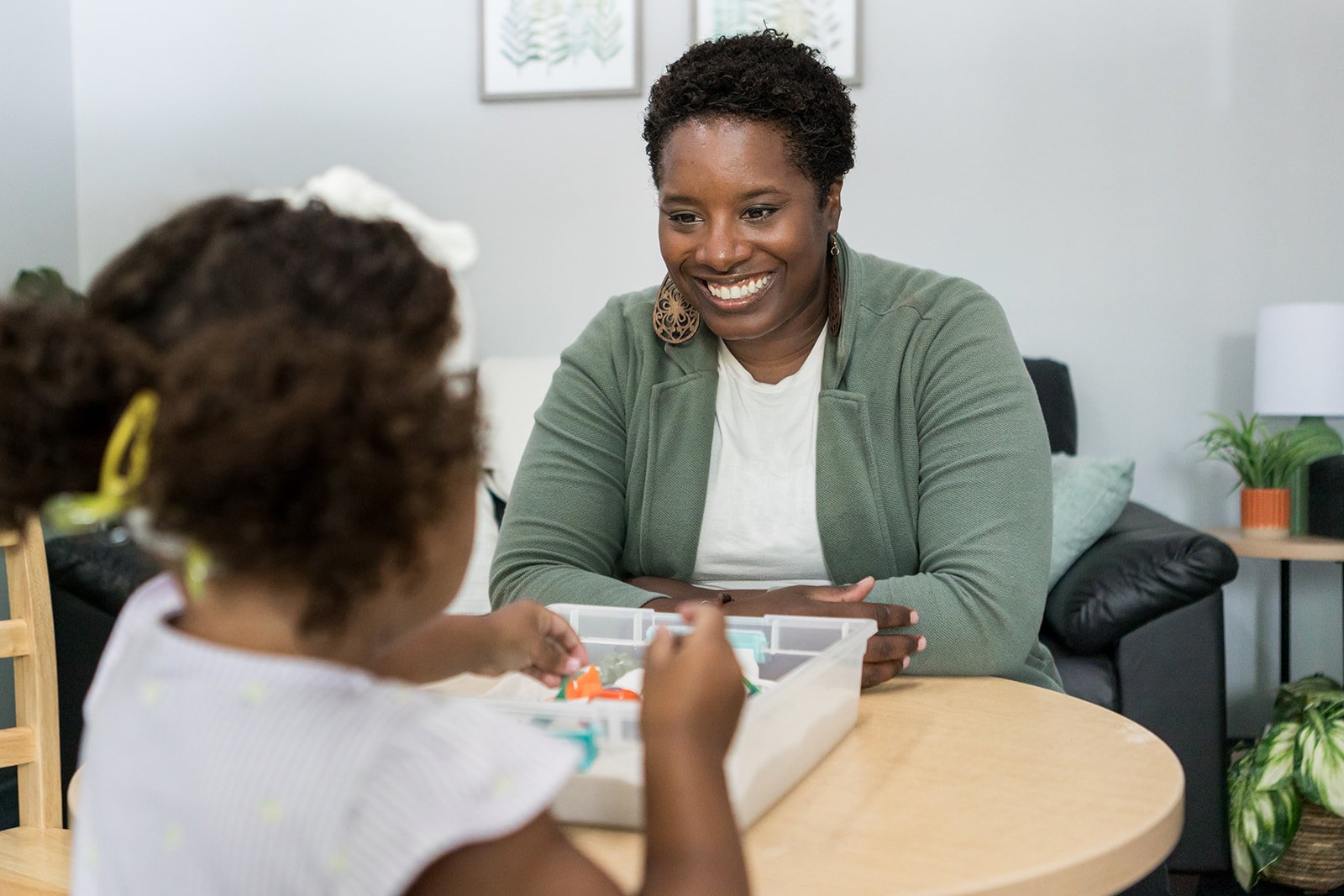 Child arranging plush dolls in a dollhouse with decorated walls, stairs, and furniture.