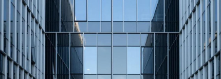 Modern office building glass facade reflecting blue sky, illustrating commercial window tinting in Charlotte NC