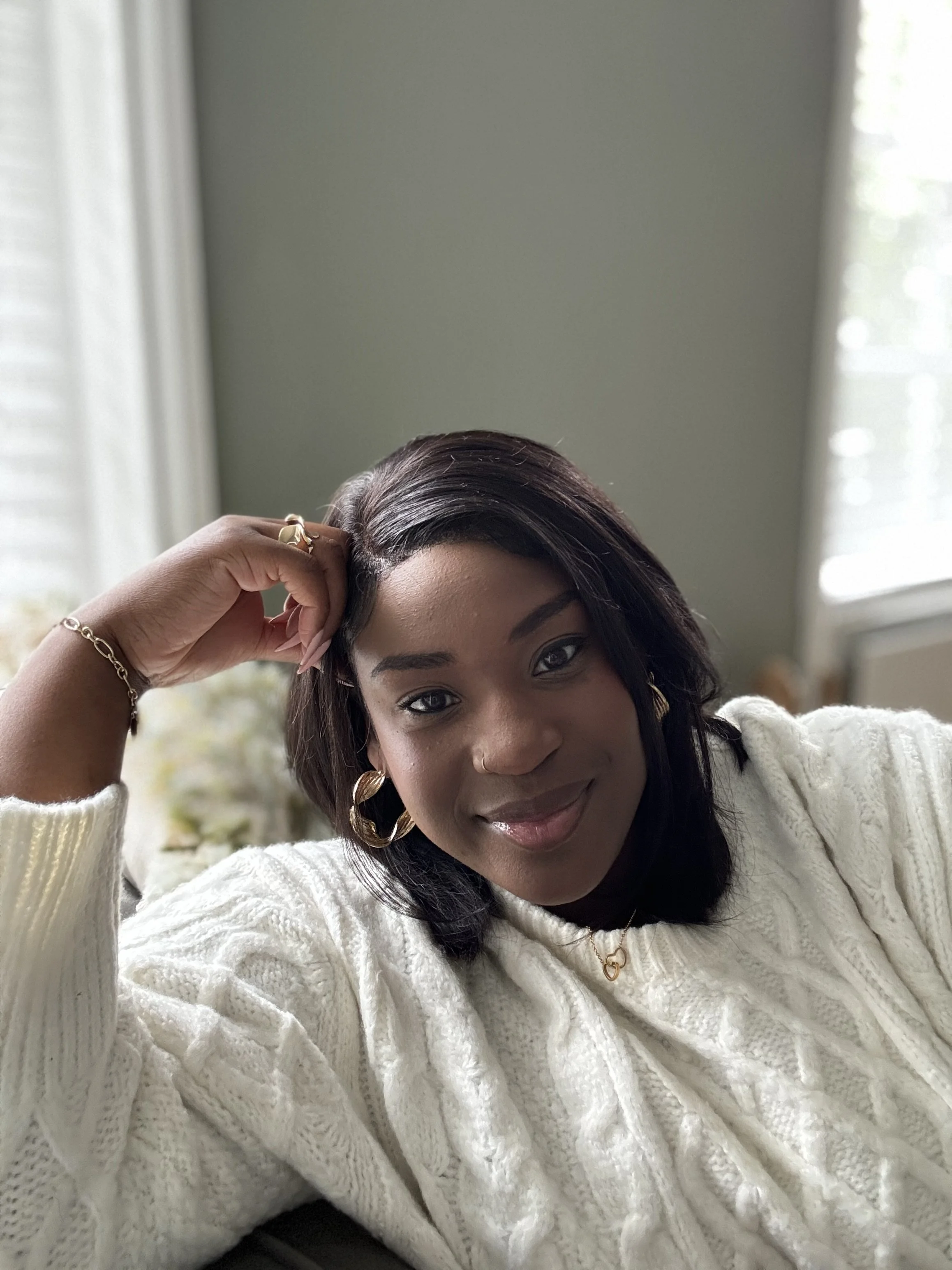 Bonita Carmel relaxing on a sofa, smiling gently—offering a calm, supportive presence to help high-achieving women silence self-doubt and live in alignment with their true selves.