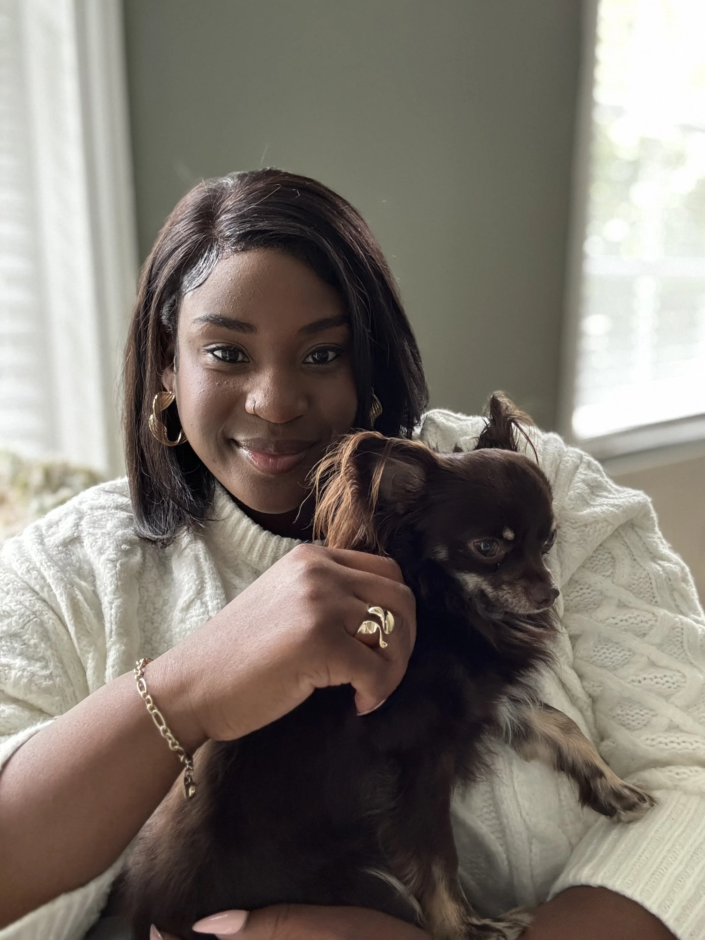 Bonita Carmel gently holding her dog, with a warm and reassuring expression—symbolising her personal commitment to creating a safe, compassionate space for women to feel seen, supported, and empowered.
