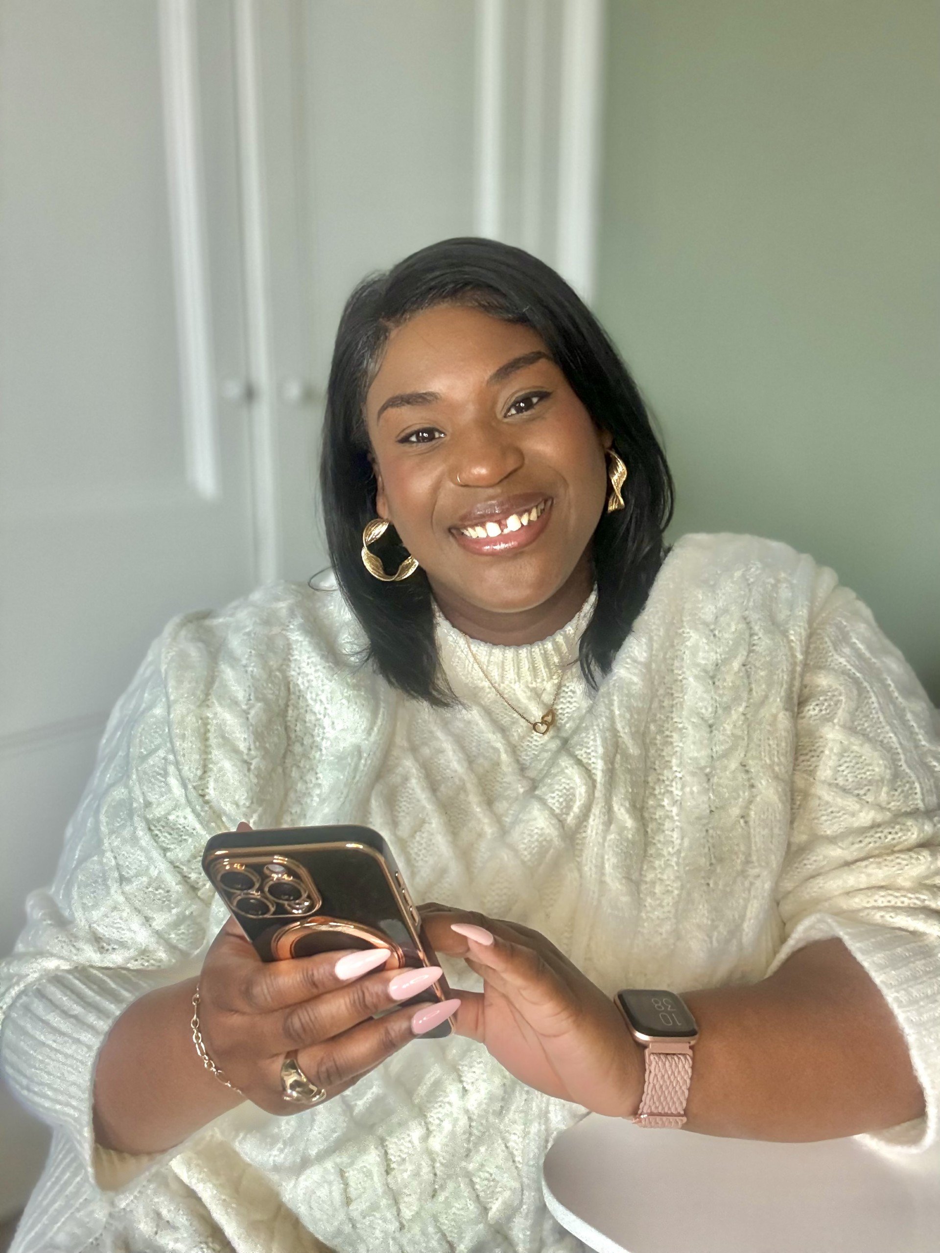 Bonita Carmel smiling brightly while holding her phone—capturing her joyful, grounded energy and passion for helping ambitious women reconnect with their true selves.
