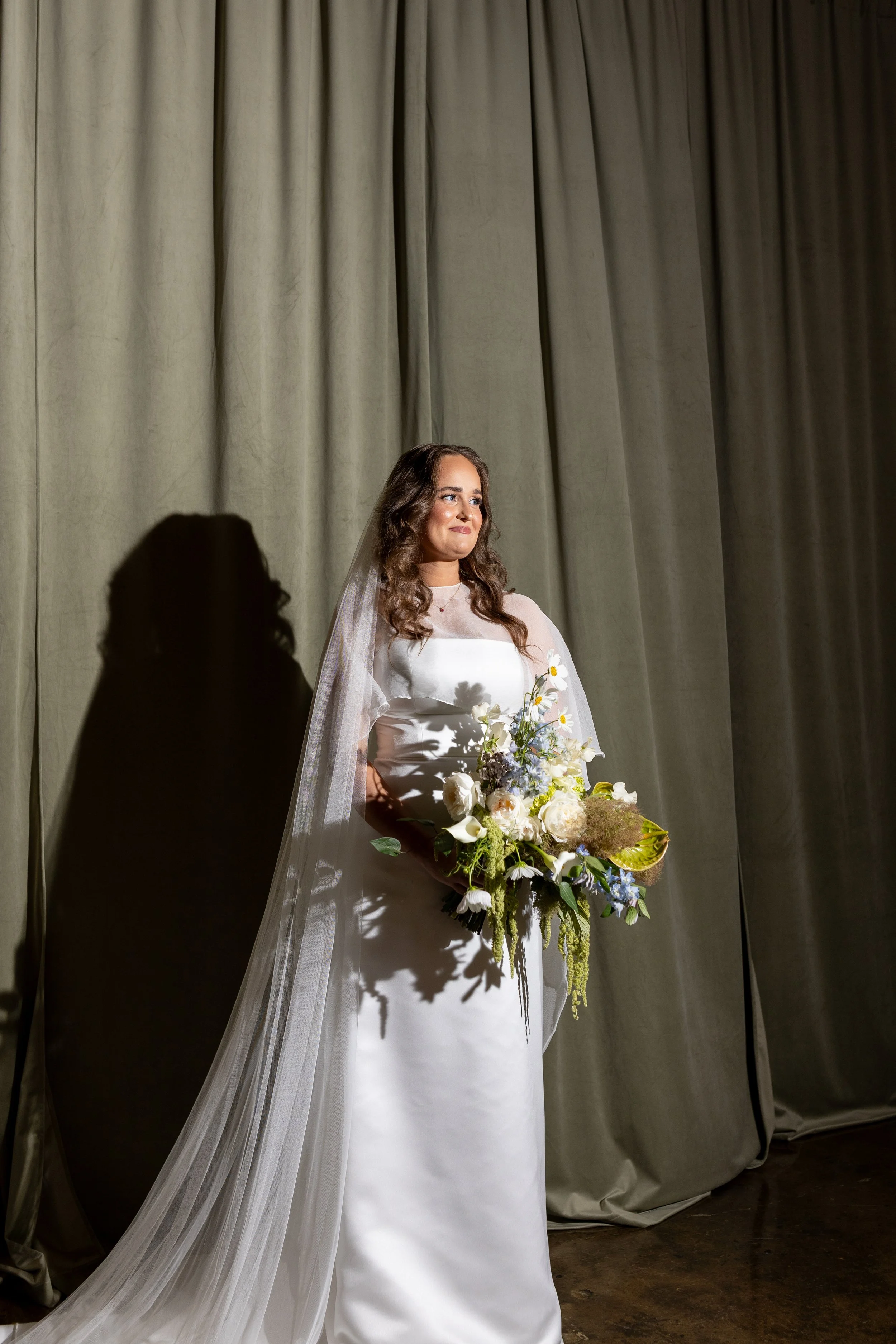 A portrait of Gracie in front of a velvet green curtain.
