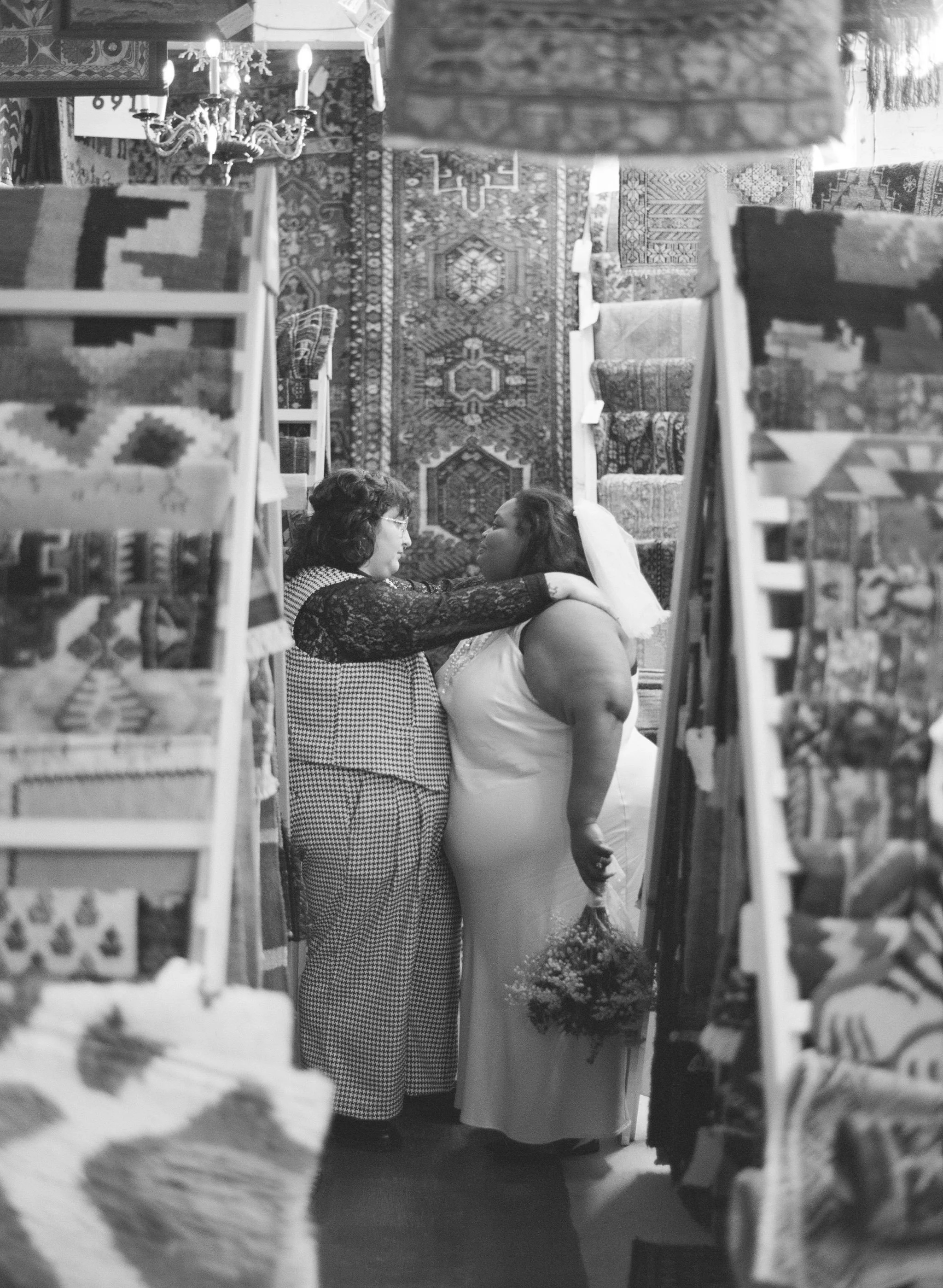 A couple in their wedding attire in front of a rug display at River Market Antiques