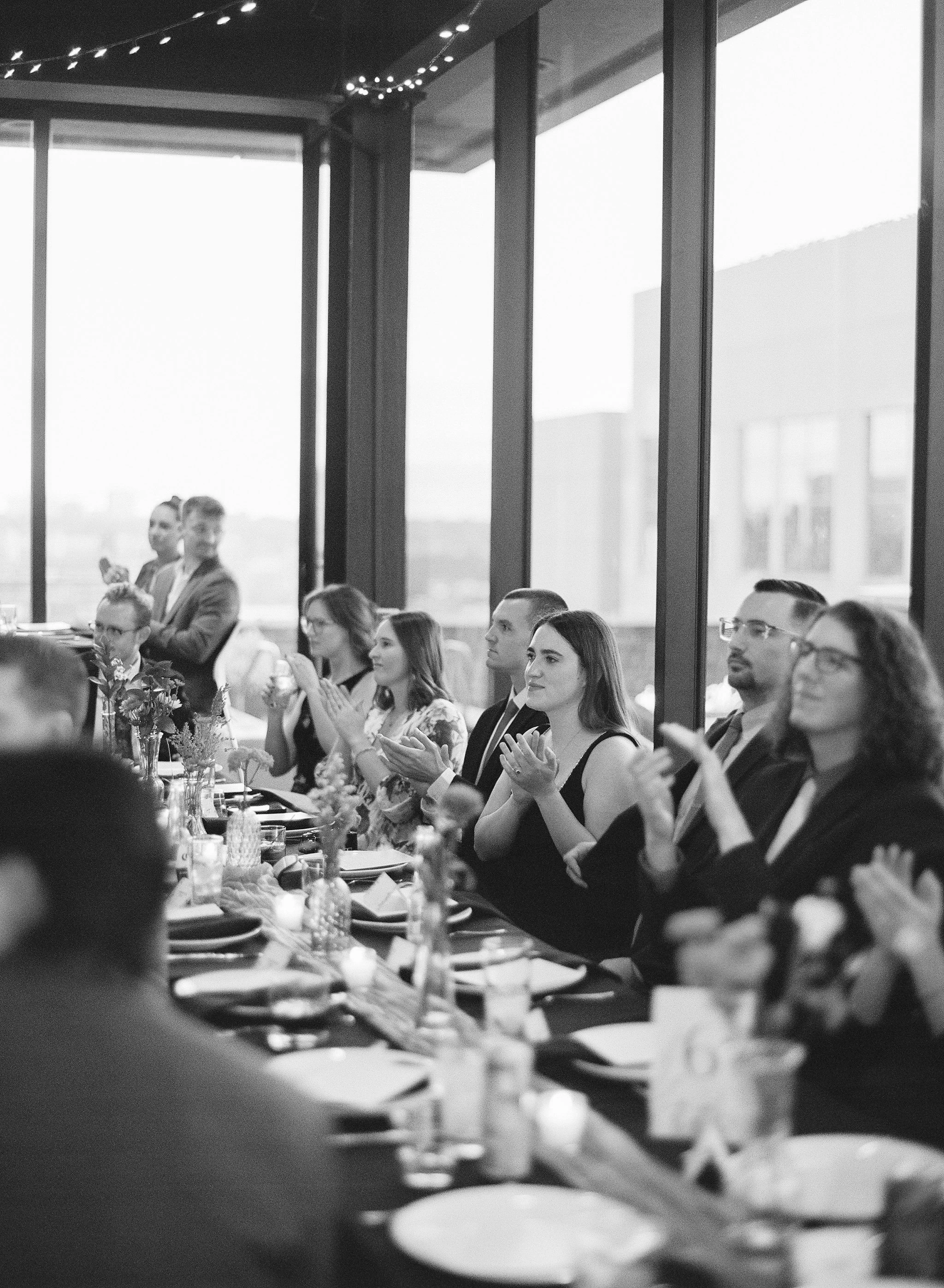 Guests clapping at their tables inside at three points.
