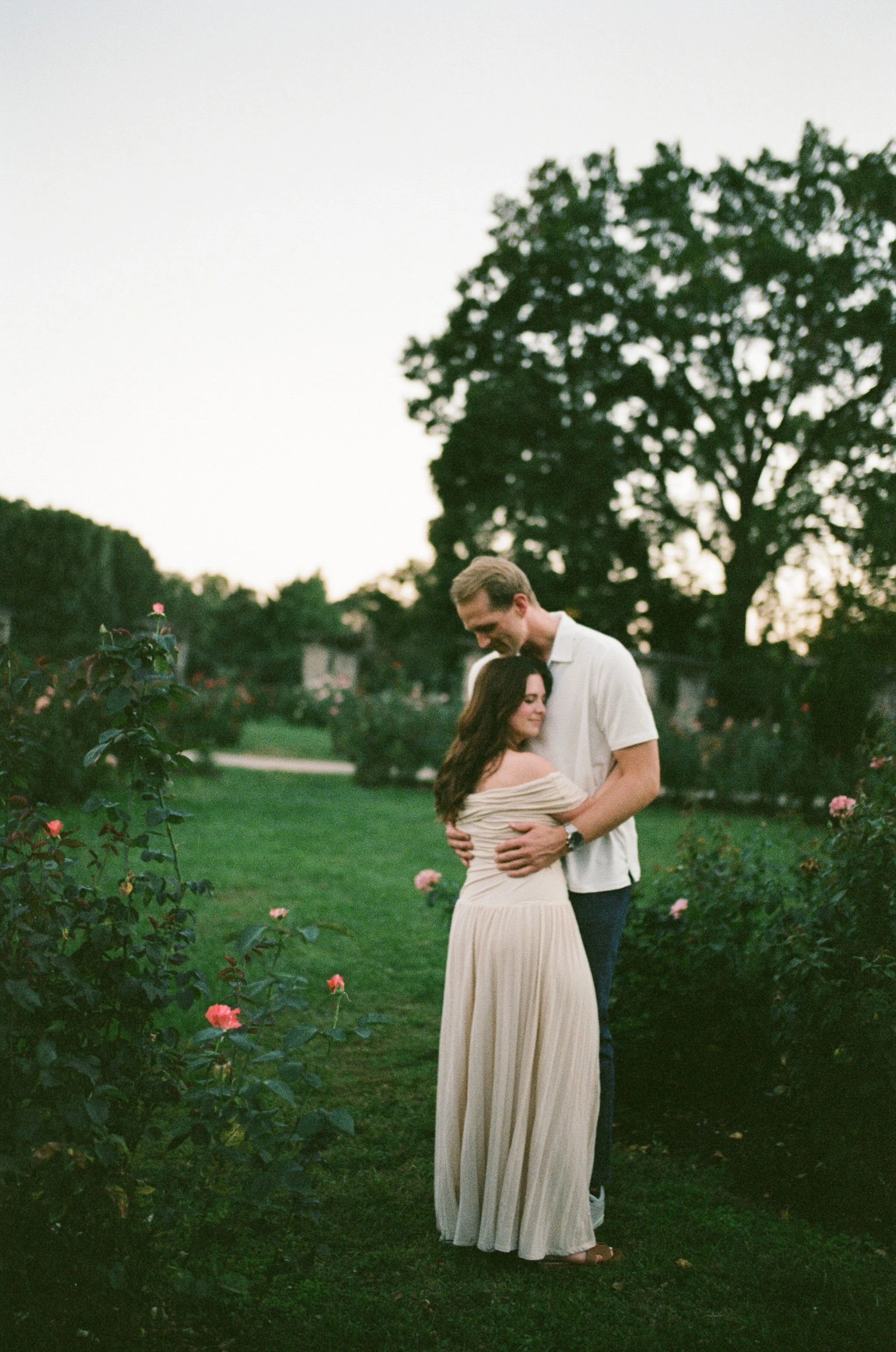 Couple embracing in the loose park rose garden.