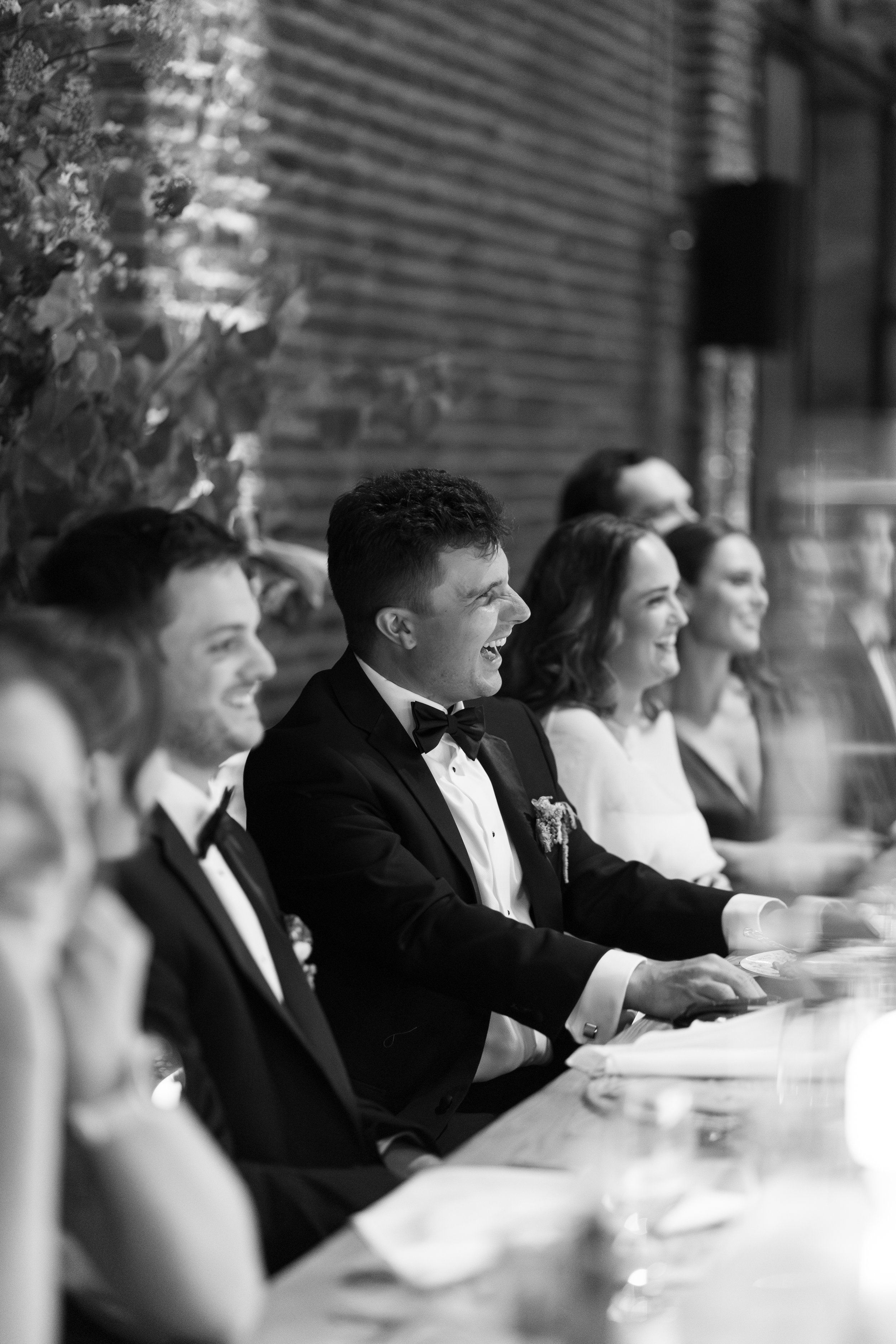 A groom smiling and laughing during toasts.