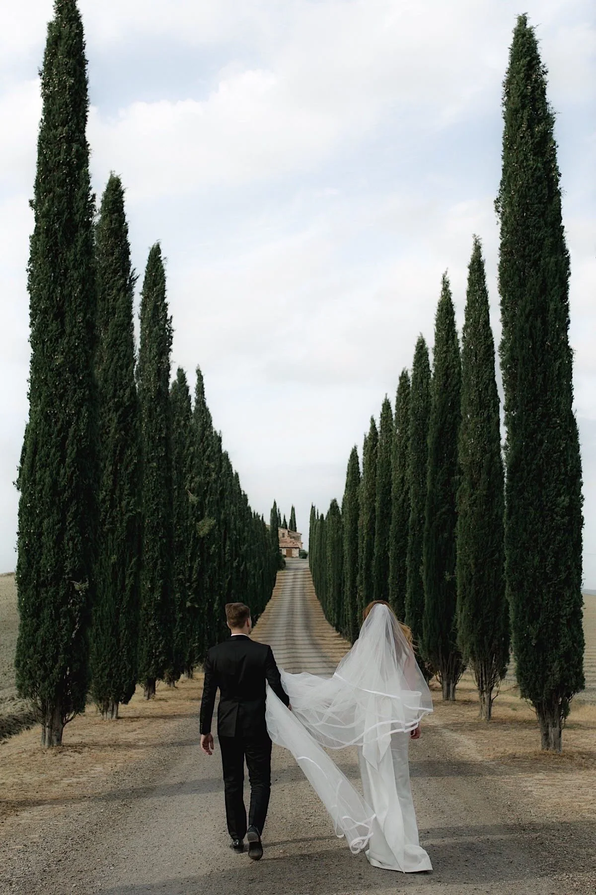 Bride and groom walking on a tree-lined path