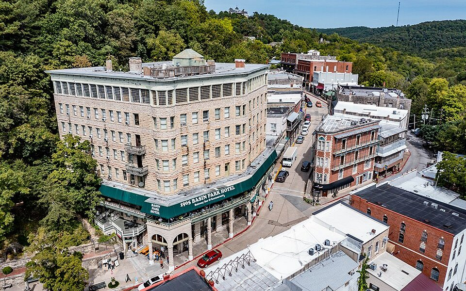 Aerial view of the Basin Park Hotel's limestone facade rising from the hillside above downtown Eureka Springs, Arkansas.
