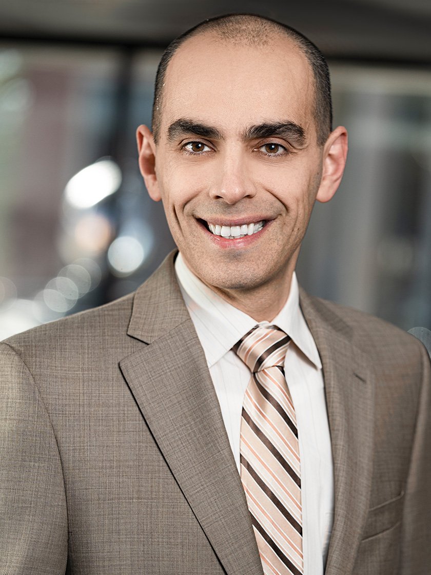 Man in a brown suit with a striped tie smiling