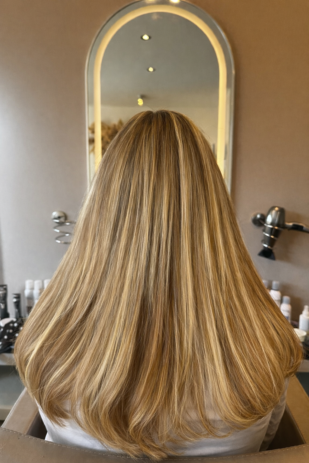 Weft extensions in lichtbruin haar met golvende punten, achteraanzicht in de salon