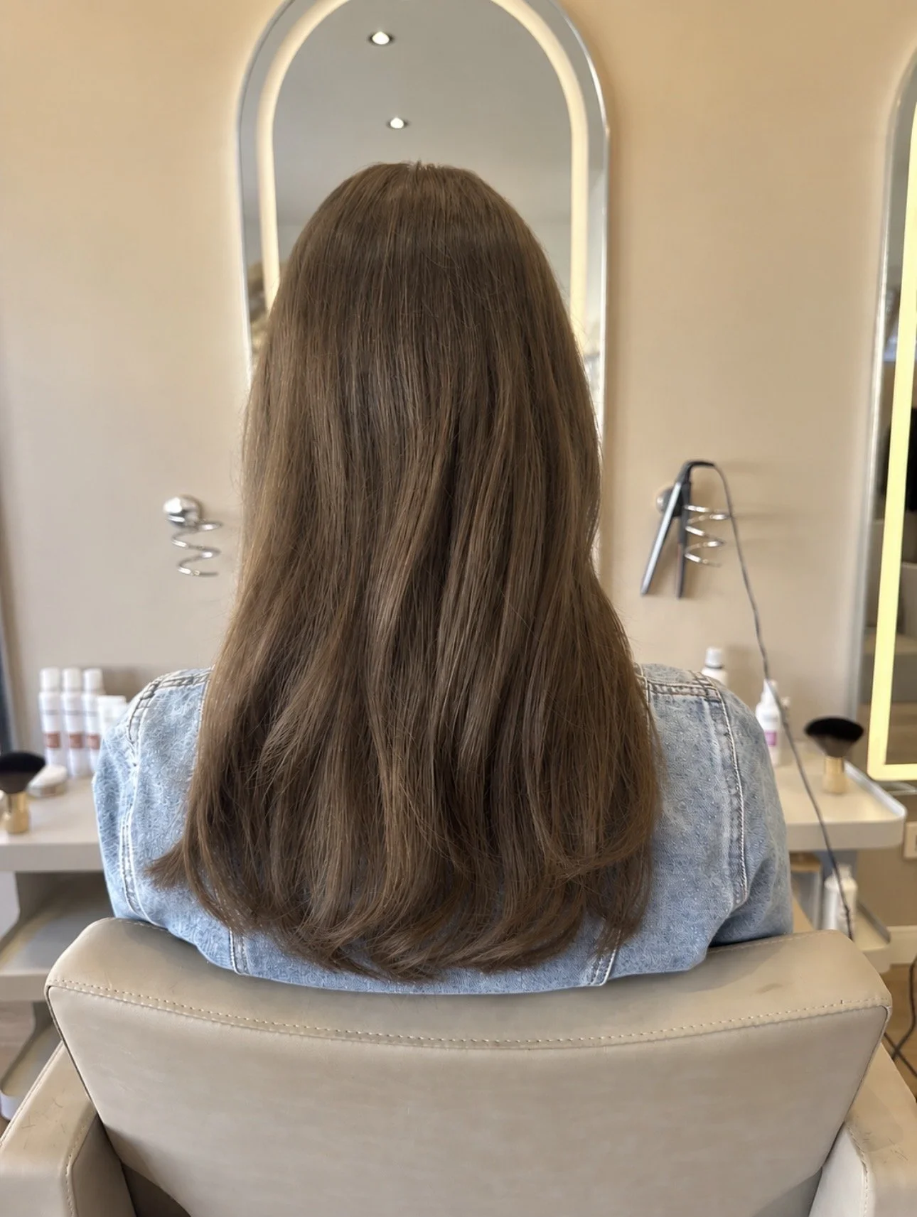 Lang bruin haar met weft extensions, achteraanzicht in de kappersstoel