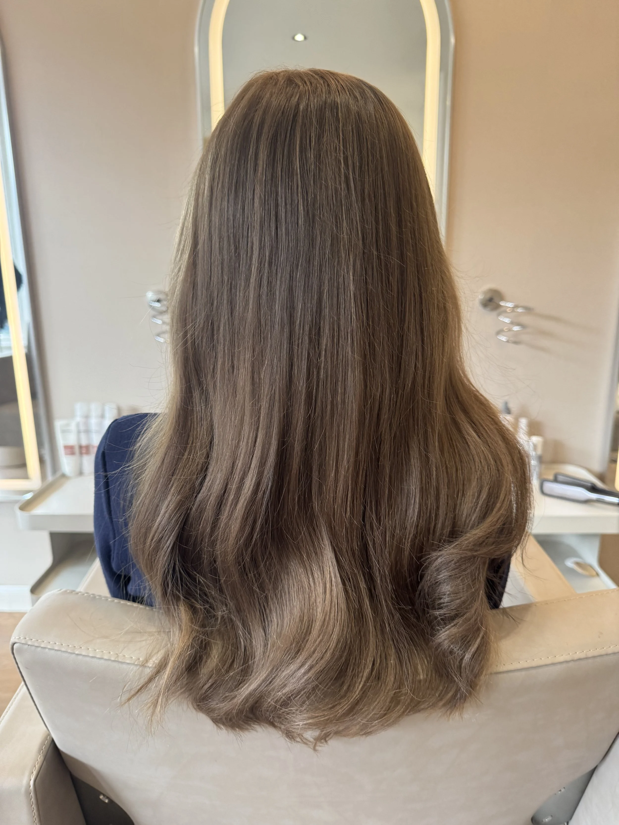 Weft extensions in lichtbruin haar met golvende punten, achteraanzicht in de salon