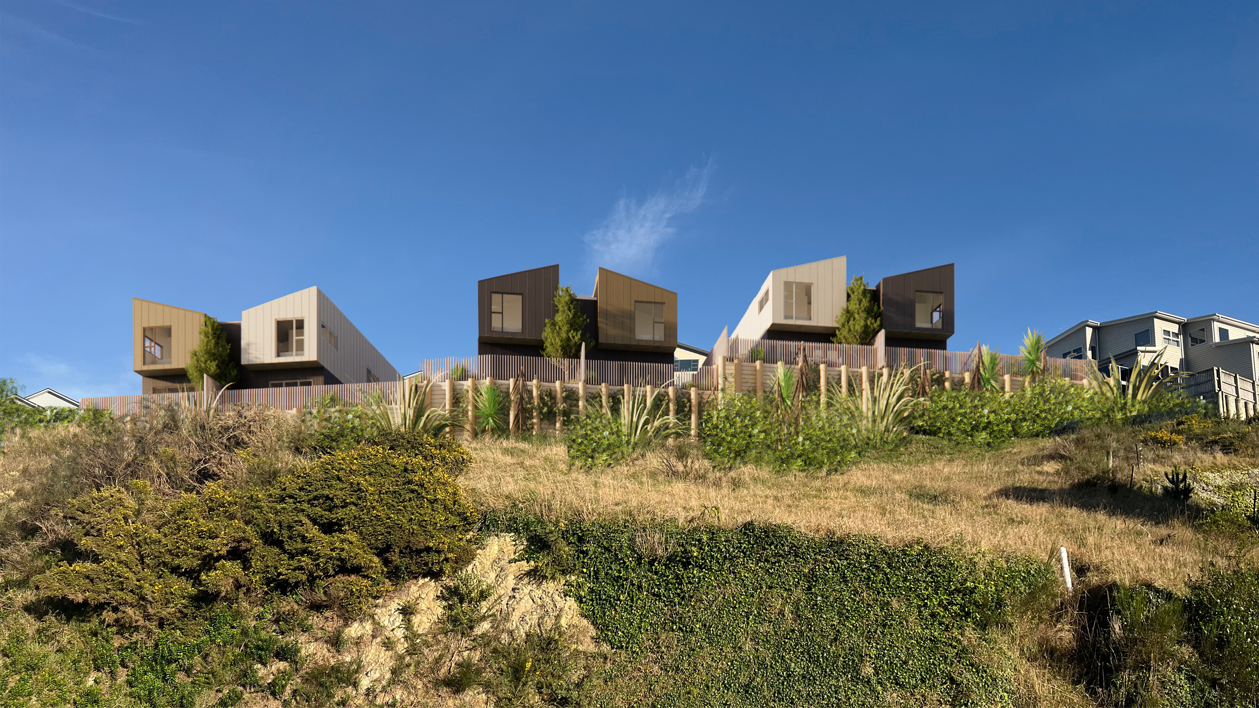 Modern houses on a hillside with clear blue sky and green vegetation in foreground.