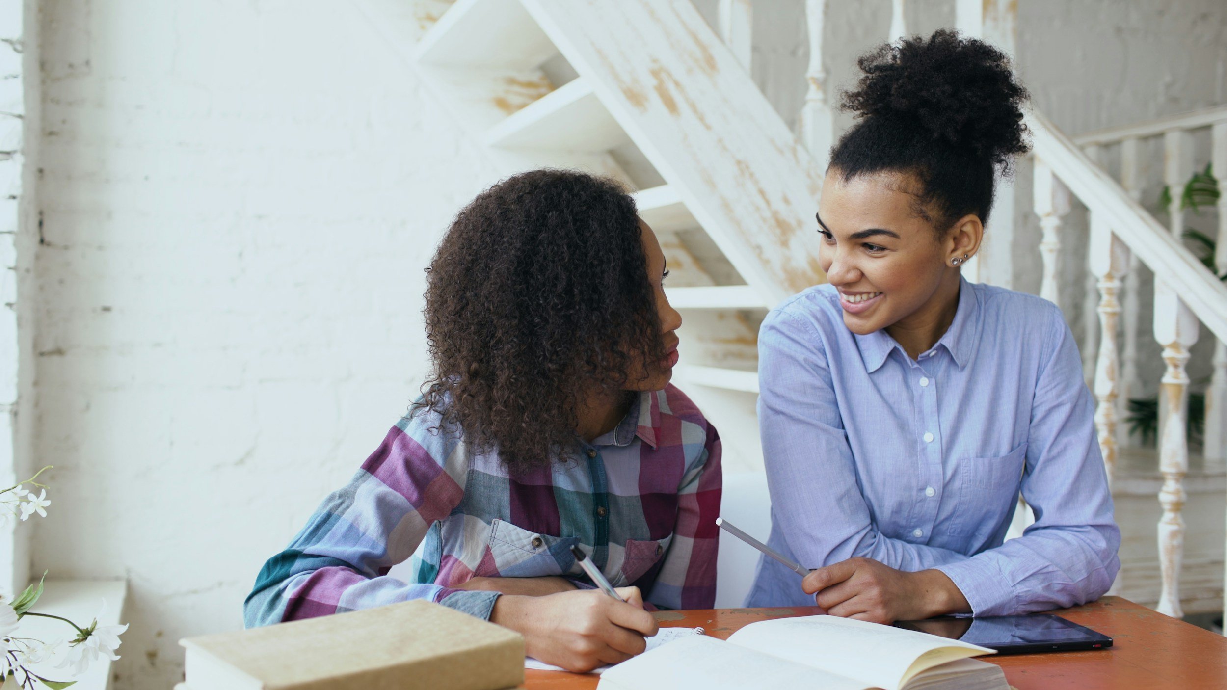 An African American woman and girl sitting at a table enjoying a conversation.