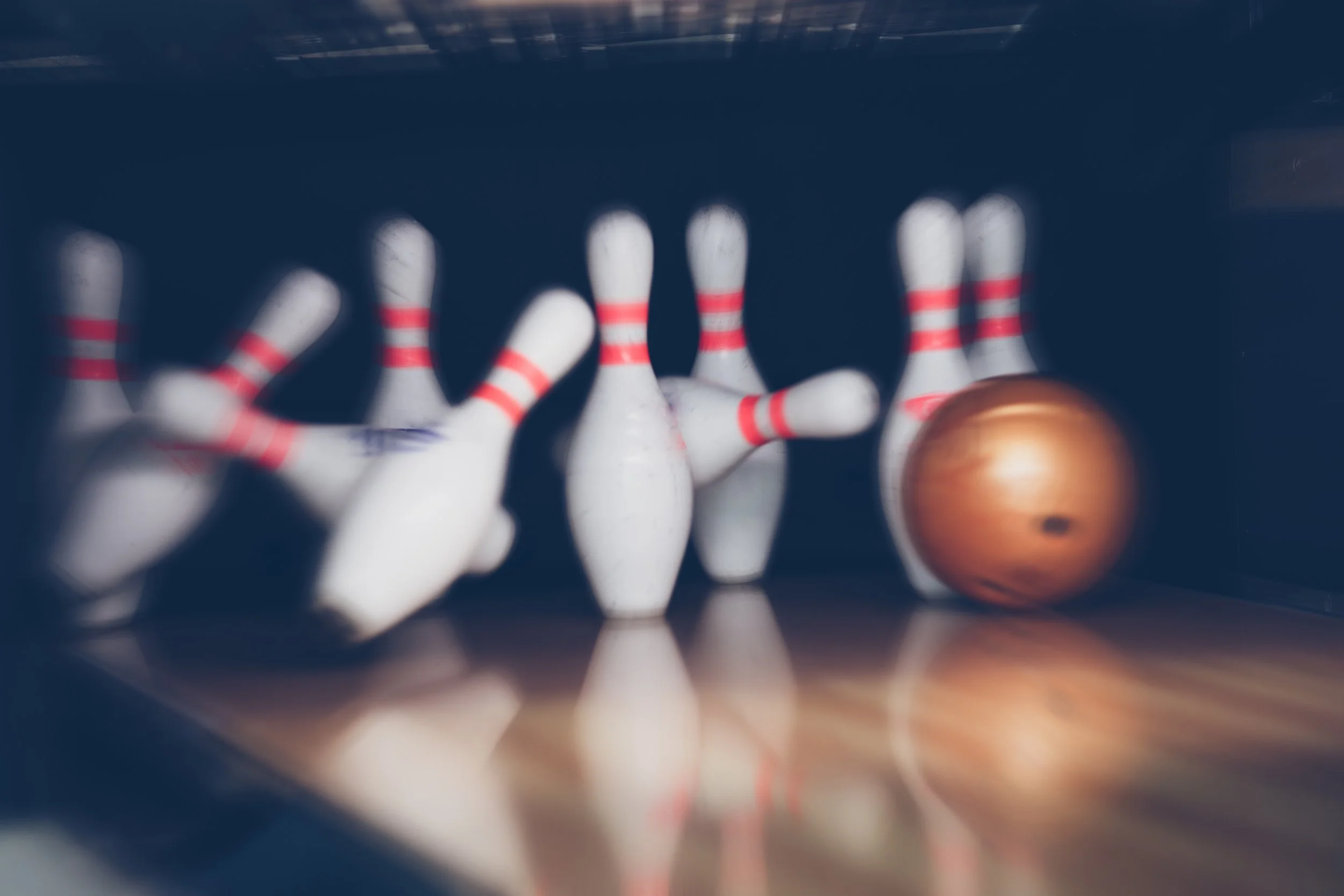 Bowling pins and a bowling ball on a bowling alley floor with the pins knocked down.