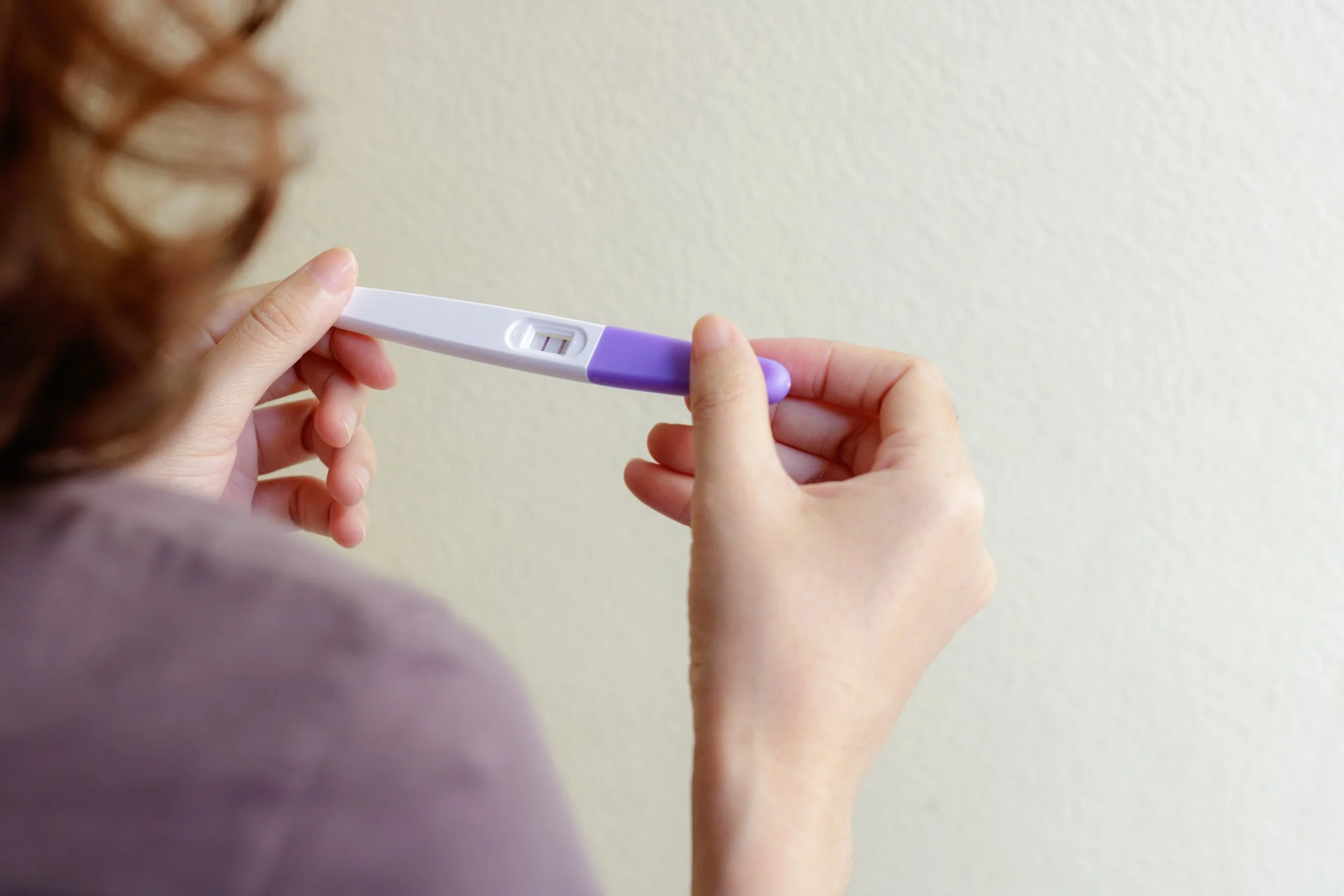 Person holding an at-home pregnancy test showing a positive result.