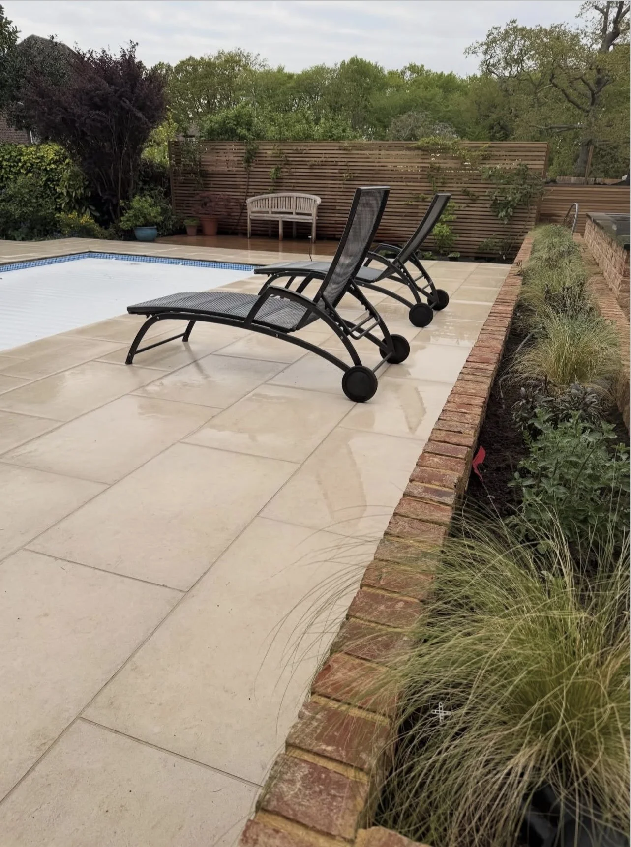 Winchmore Hill garden with deck chairs, paving, raised brick planter with perennials, and swimming pool