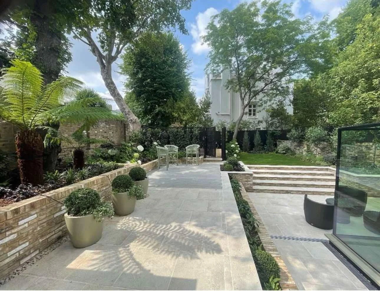 Layered lush and shade-tolerant perennials beneath mature trees in Belsize Park garden