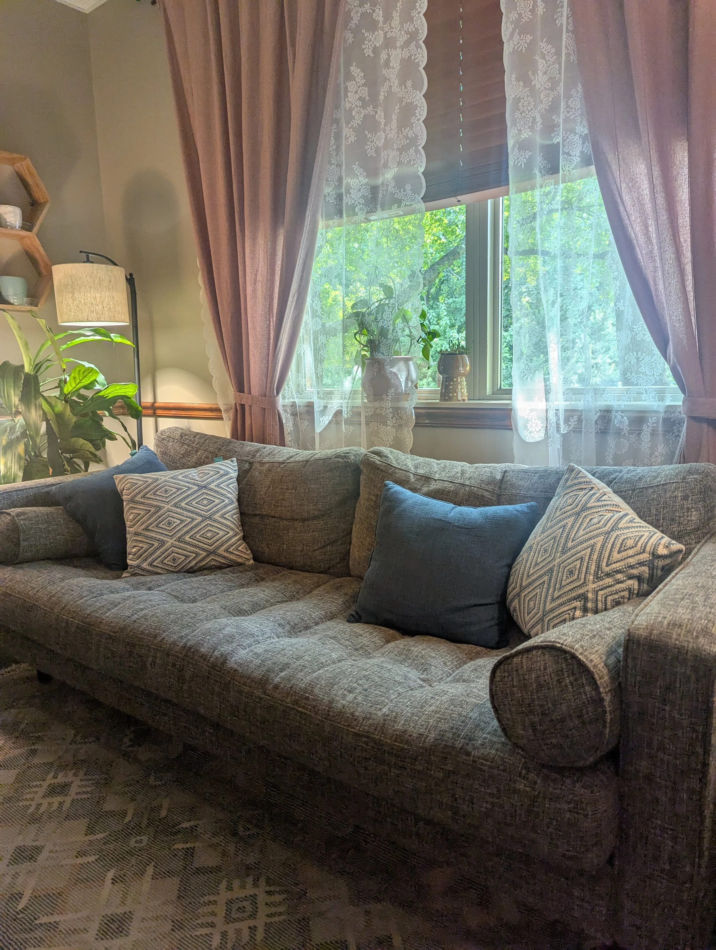Inviting Kansas City therapy office of Aimee Hubbard. Image of a gray couch, plants, and natural light for a comfortable counseling environment.