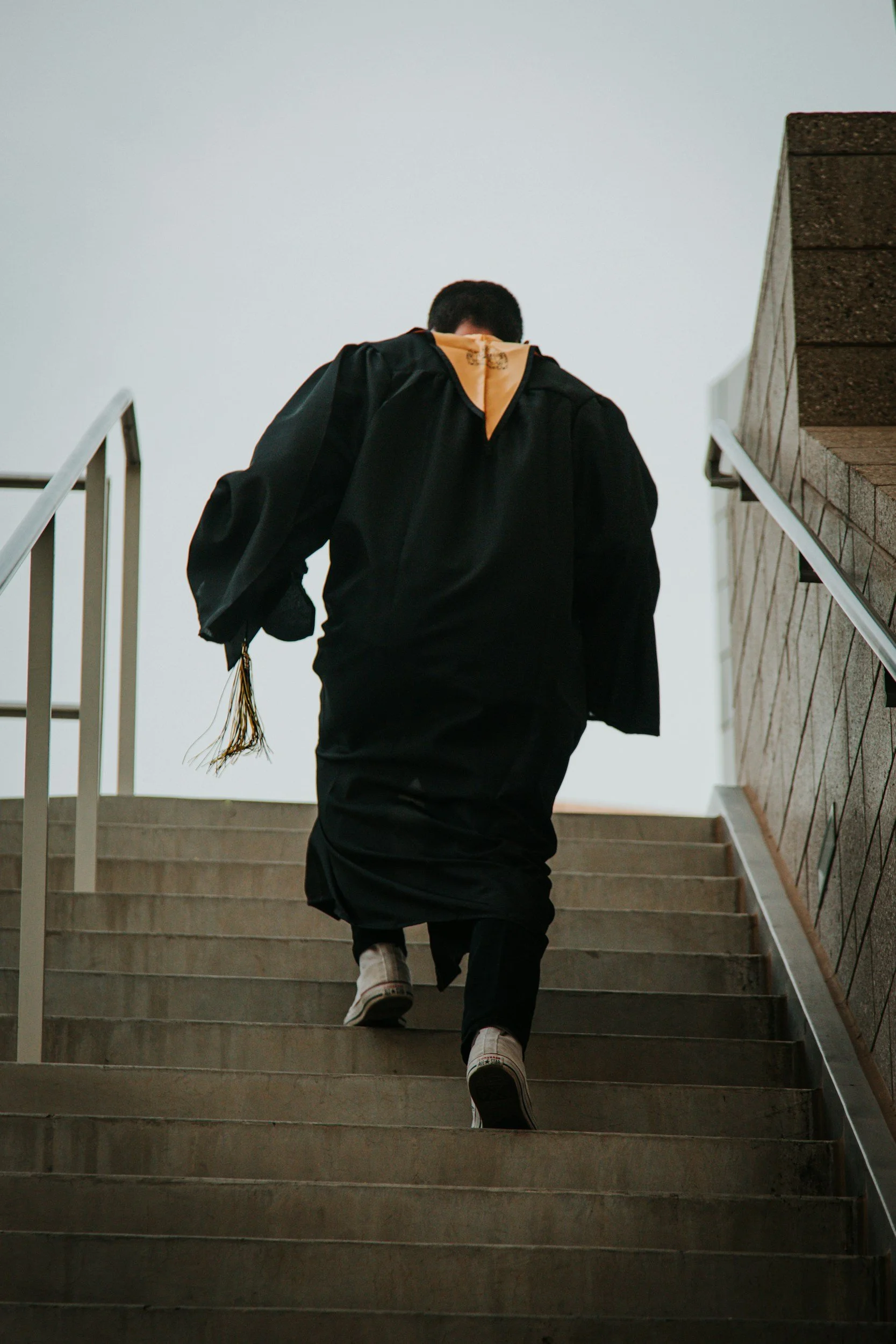 Monday.com graduated and trained person ascending outdoor staircase, viewed from below.