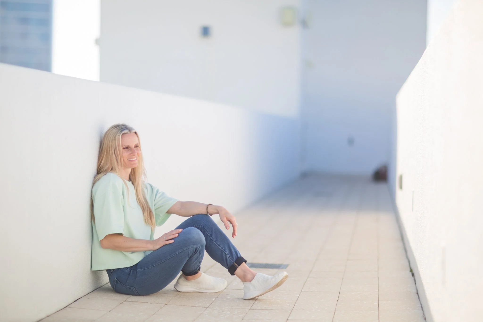 Woman sitting calmly against a wall, representing relief and recovery from OCD in Bradenton, FL
