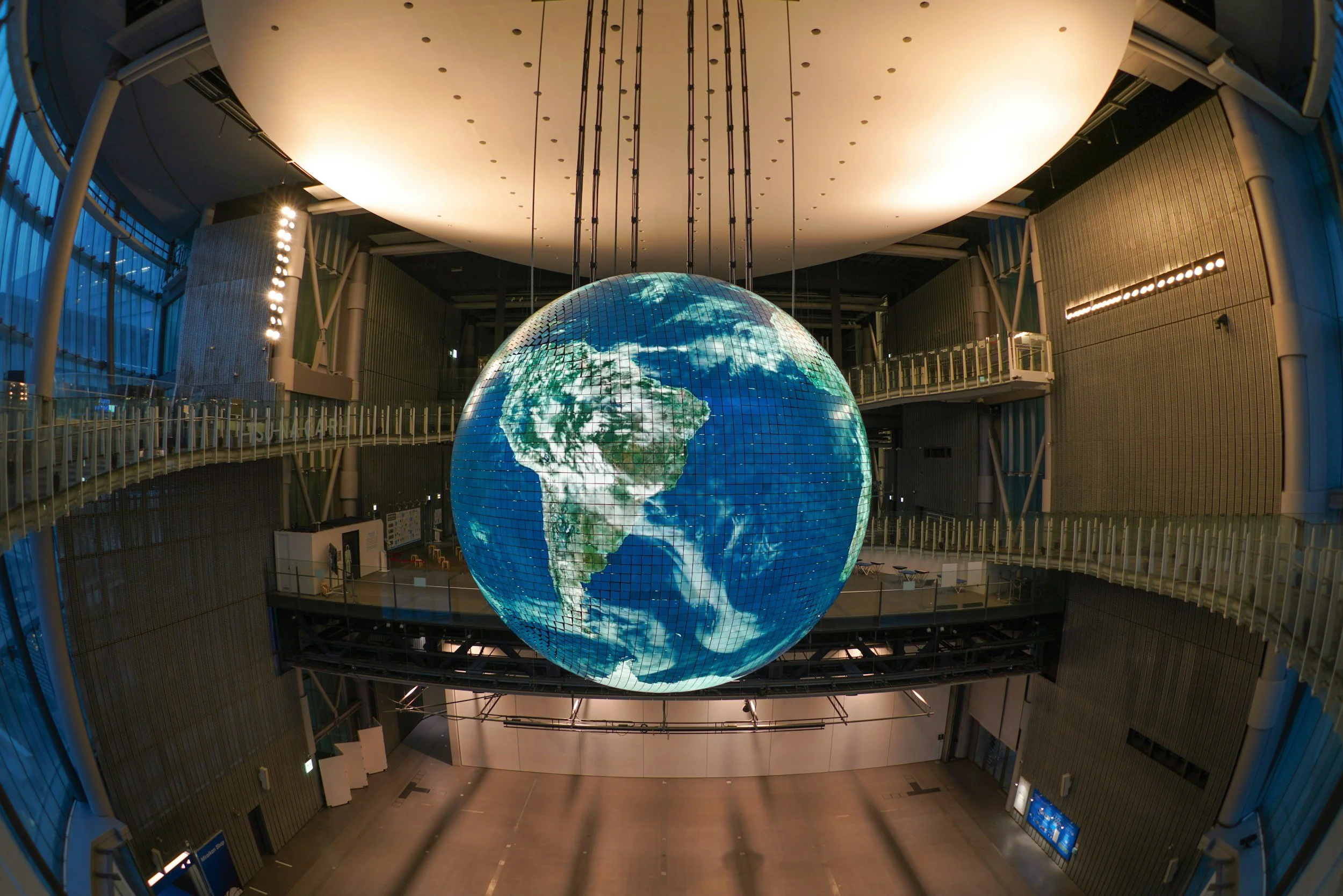 A digital circular verison of the planet Earth can be seen in the middle of a confrence room promoting an all in one solution for security in the world.