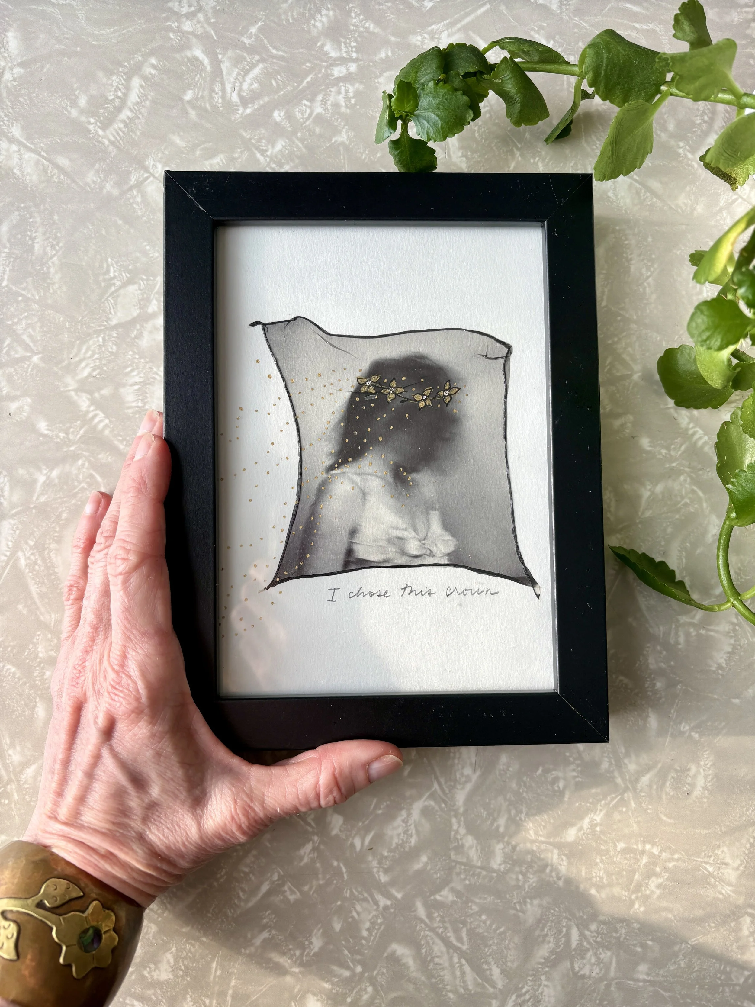 Framed Polaroid emulsion lift with ink showing a figure with a flower crown and the handwritten text "I chose this crown," held by the artist, Nikki Gardner Studio