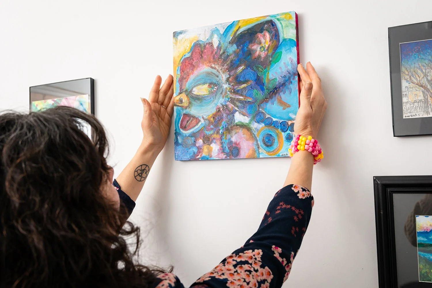 Person hanging a colorful abstract portrait in an art gallery.