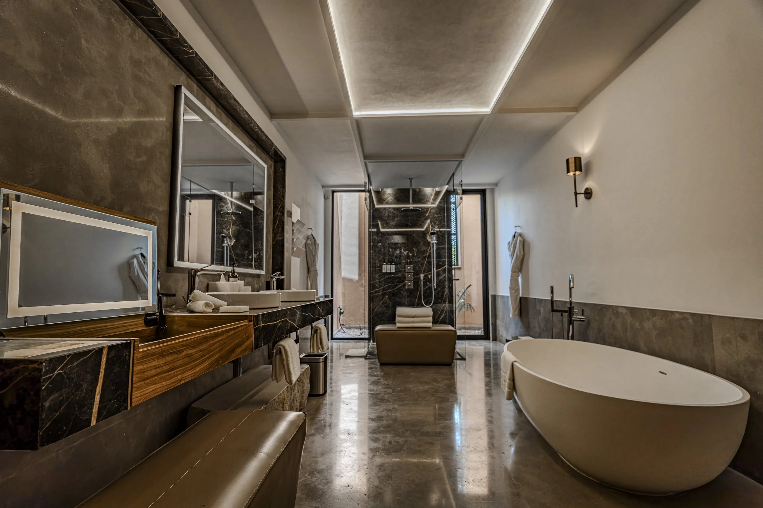 Modern bathroom featuring a large freestanding bathtub, a double sink vanity with a mirror, a walk-in shower with black marble walls, and soft lighting.