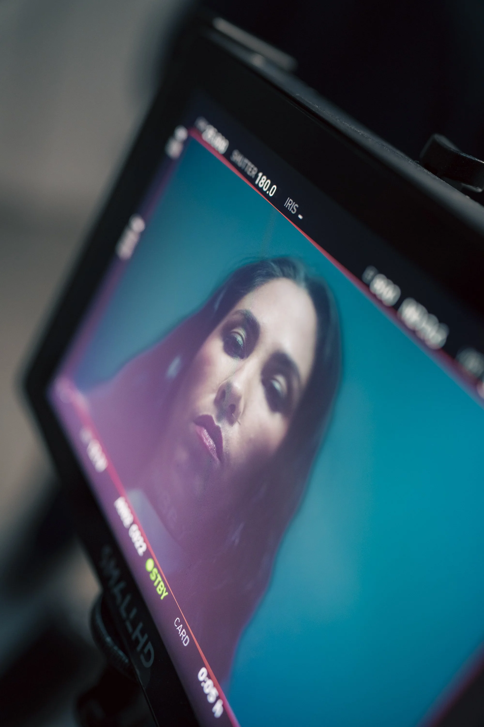 Close-up of a digital camera screen showing a portrait of a woman with makeup, dark hair, and a serious expression.