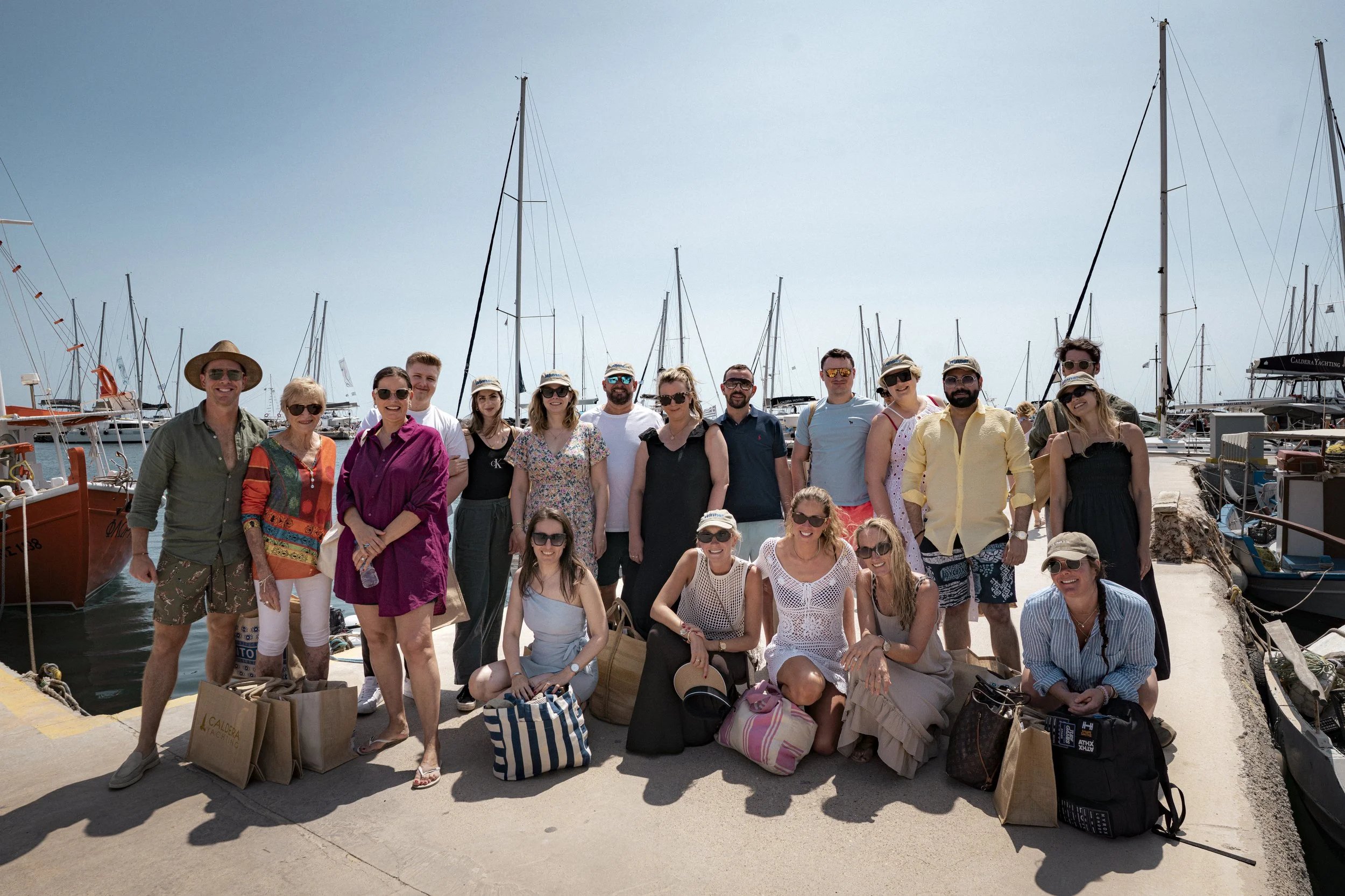 Group of people posing on a dock with sailboats and yachts in the background