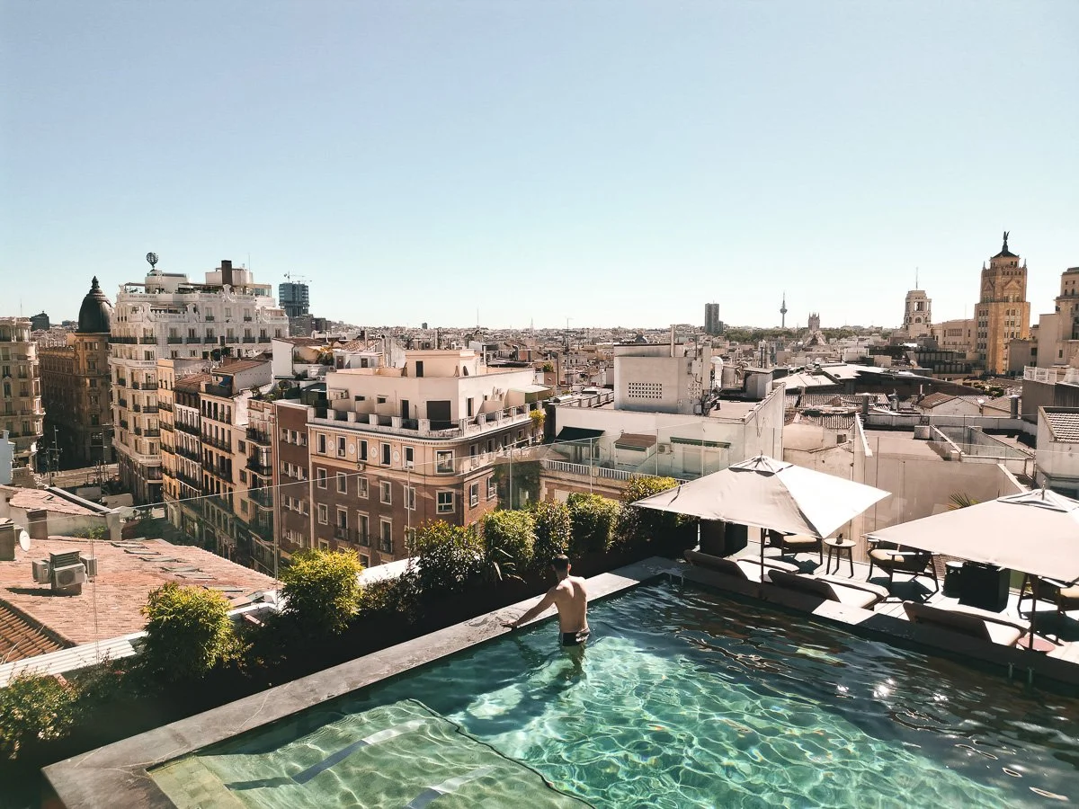 A rooftop pool overlooking a city skyline with tall buildings and clear blue sky.