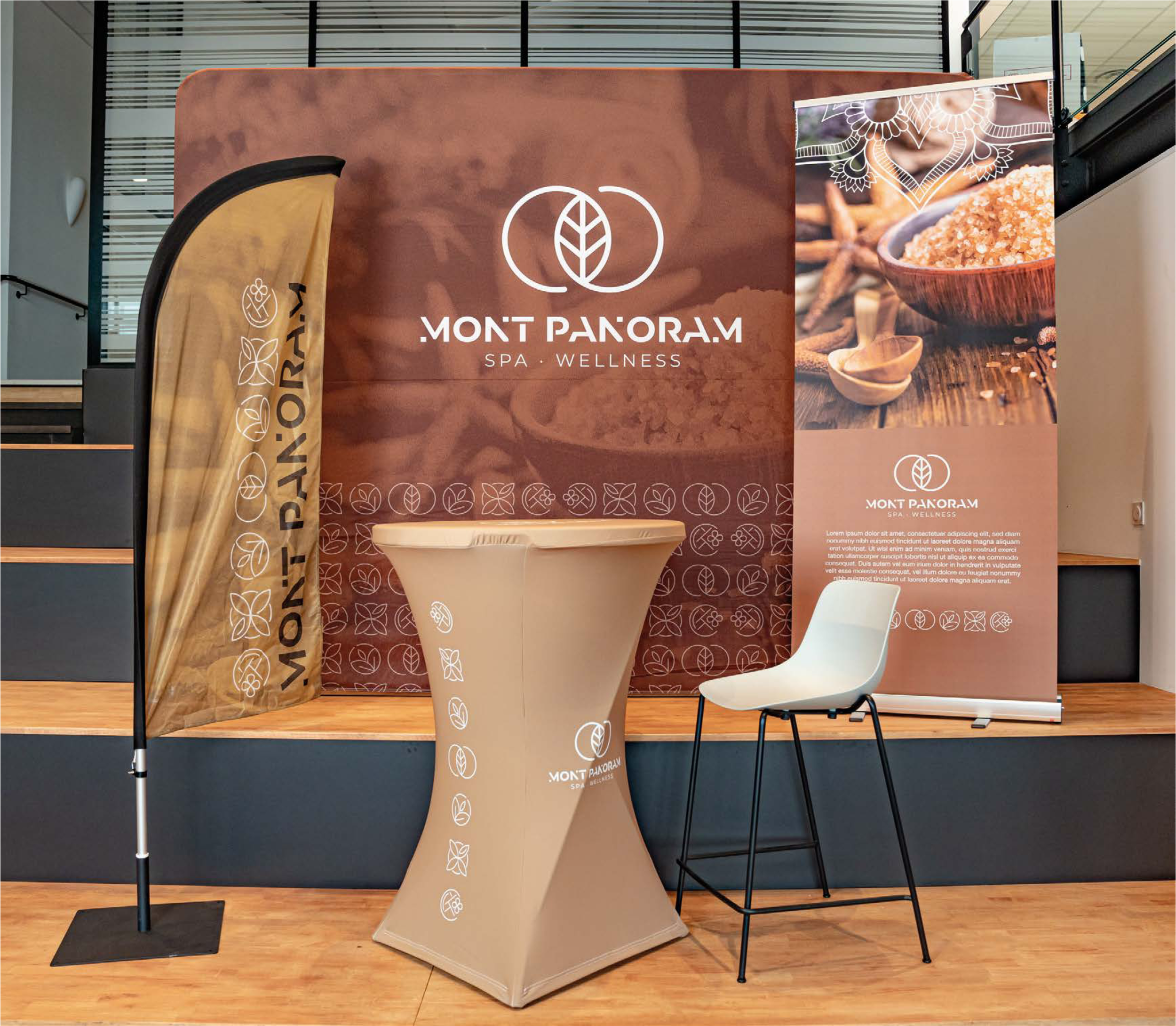 Stands promotionnels pour le spa Mont Panorama, avec un panneau principal, une bannière et un pupitre, tous arborant le logo de l'établissement et des motifs de feuilles. L'ambiance évoque le bien-être et la relaxation.