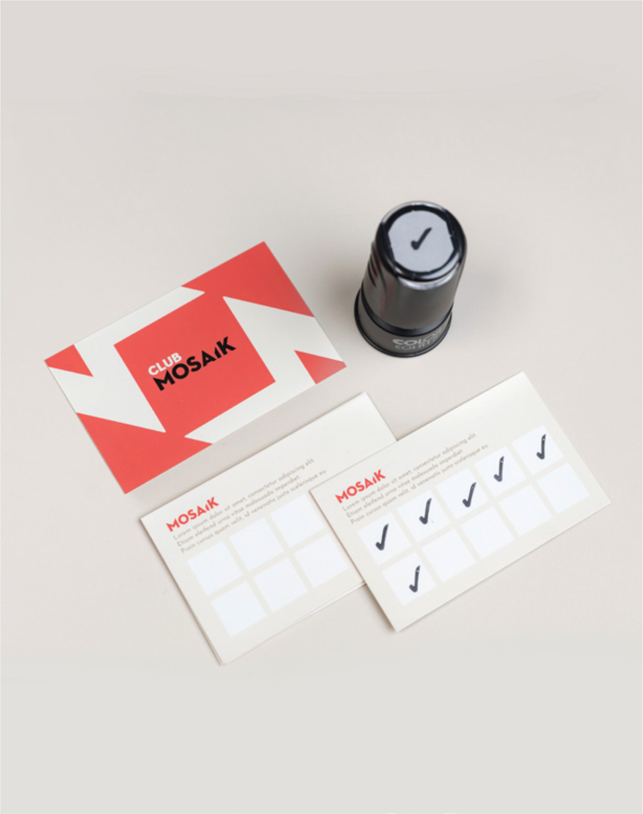 Everest, un tampon encreur noir avec un cercle où est dessinée une coche, deux feuilles de papier avec des cases à cocher, une carte de visite ou carte de membre avec le texte "CLUB MOSAIK".