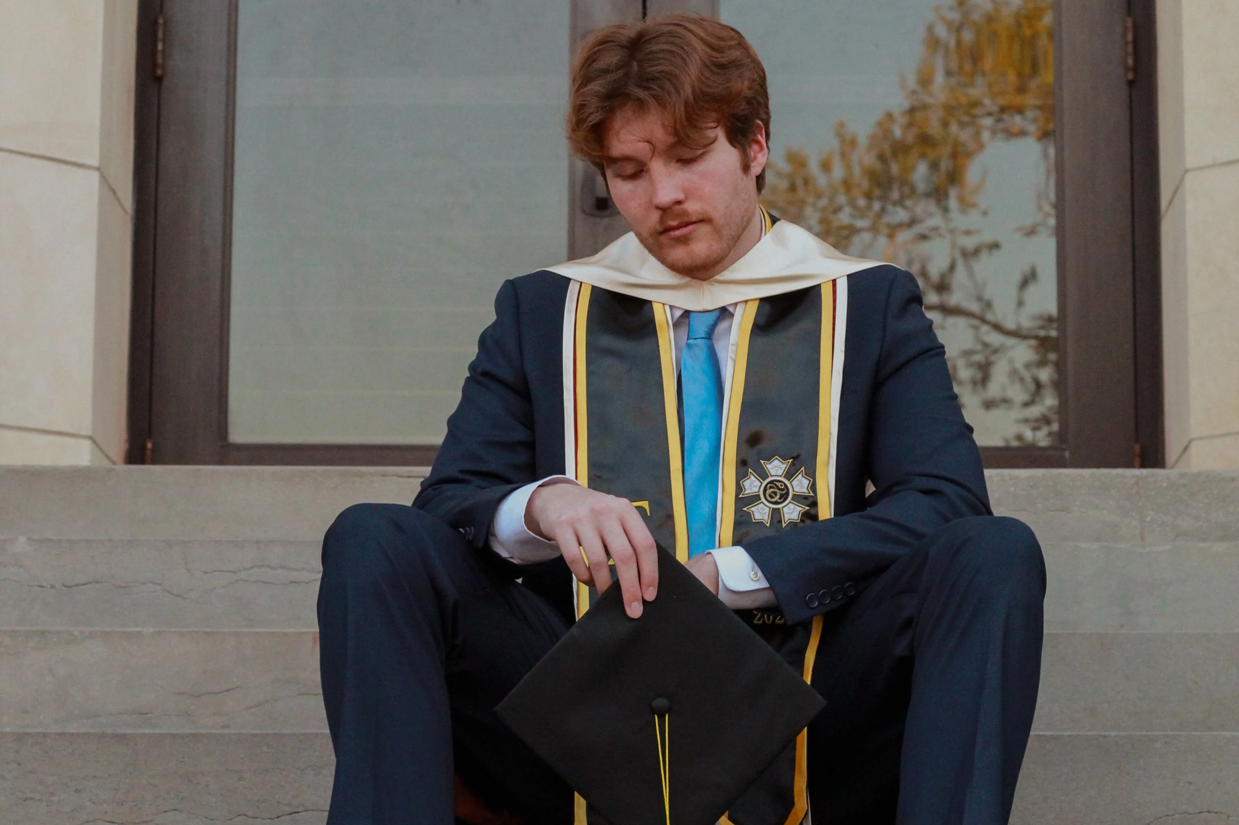 a male college grad posing on stairs during sunset