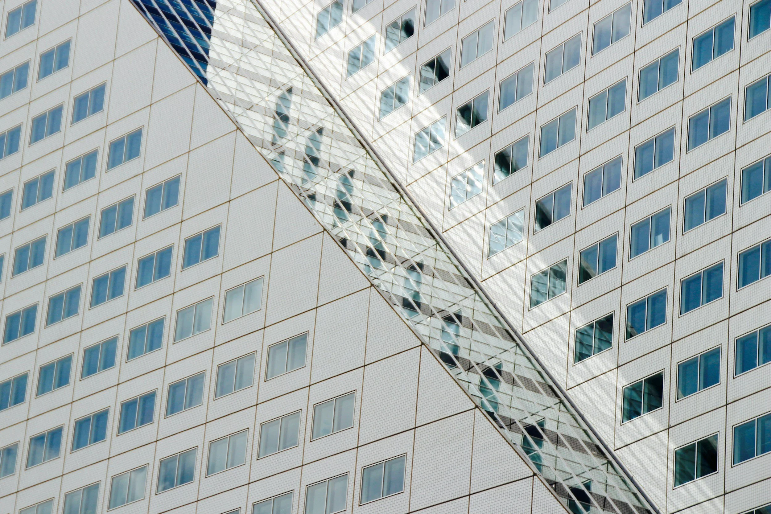 Close-up of a modern tall building with a distinctive diamond-shaped glass pattern on its facade and numerous small rectangular windows.