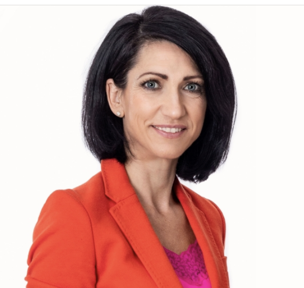 Professional woman with shoulder-length black hair, wearing an orange blazer and pink top, smiling against a white background.