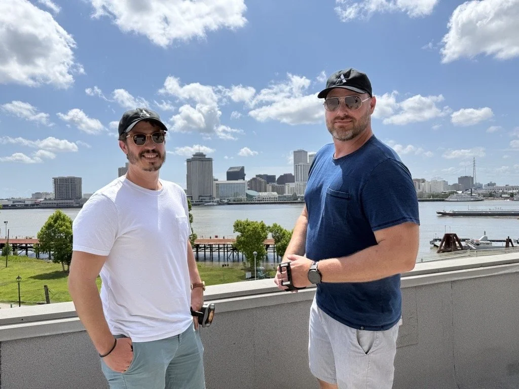 the CEO and Chief Engineer stand on a balcony looking at the Mississippi River and New Orleans skyline.