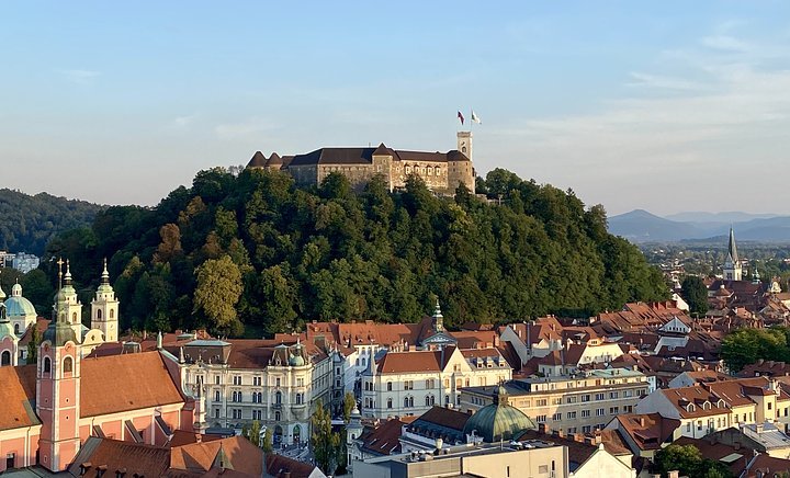 A castle on a hill overlooking a city with historic buildings and church spires.